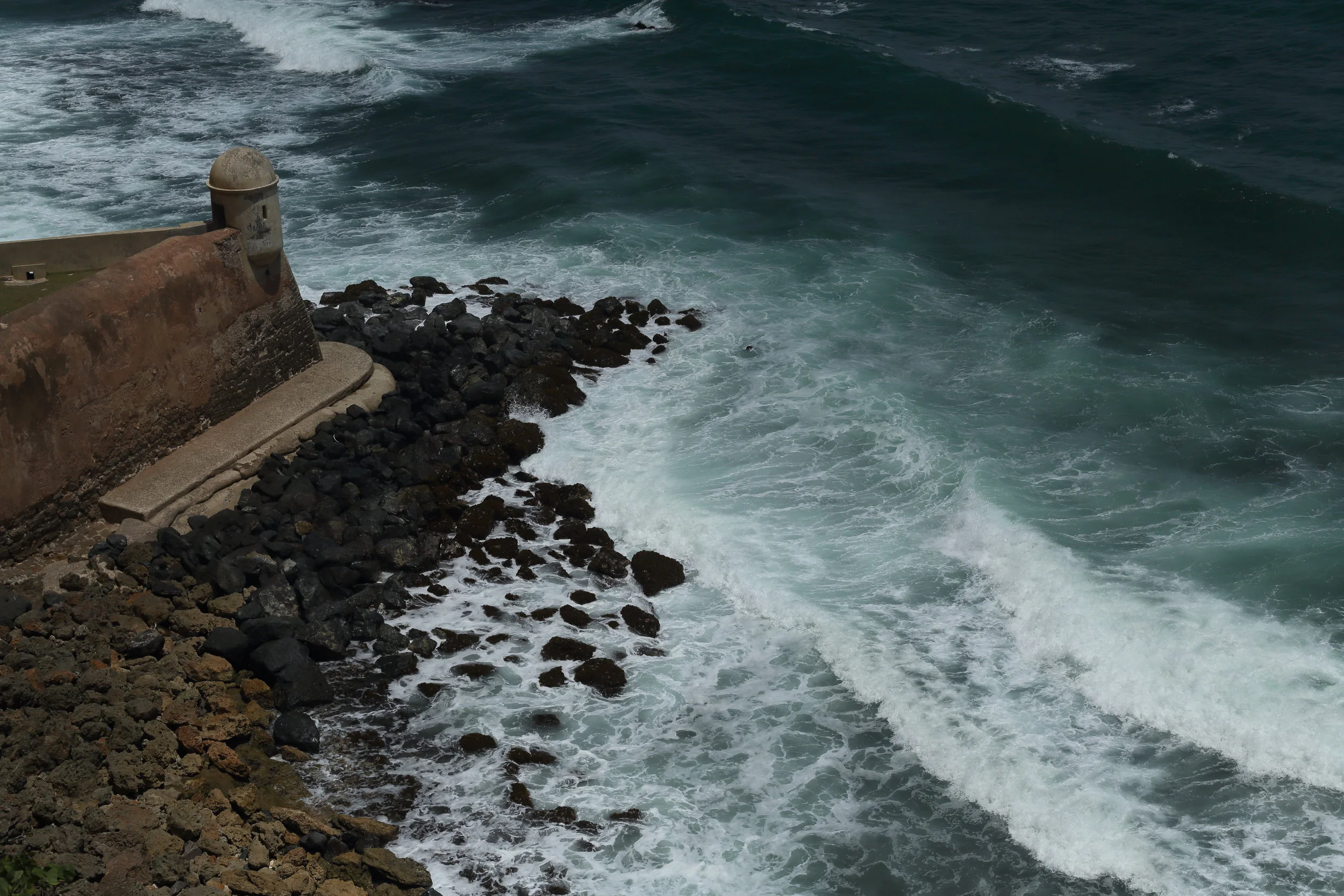 This Garita Del Diablo is said to be haunted. A Spanish soldier named Sanchez disappeared one night when assigned to stand guard at this sentry box. It is the most remote garita in the fort, and the sounds of the crashing waves below would mask any calls for help. Later on, when I was walking down the coast with this sight still in view, I talked to a local who told me Garita Del Diablo caused hurricane María. He also said that sharks only appear on this side of the coast, and that the rocky shoals there were most dangerous—swimmers get sucked inside and drown while the waves beat them against the rocks.