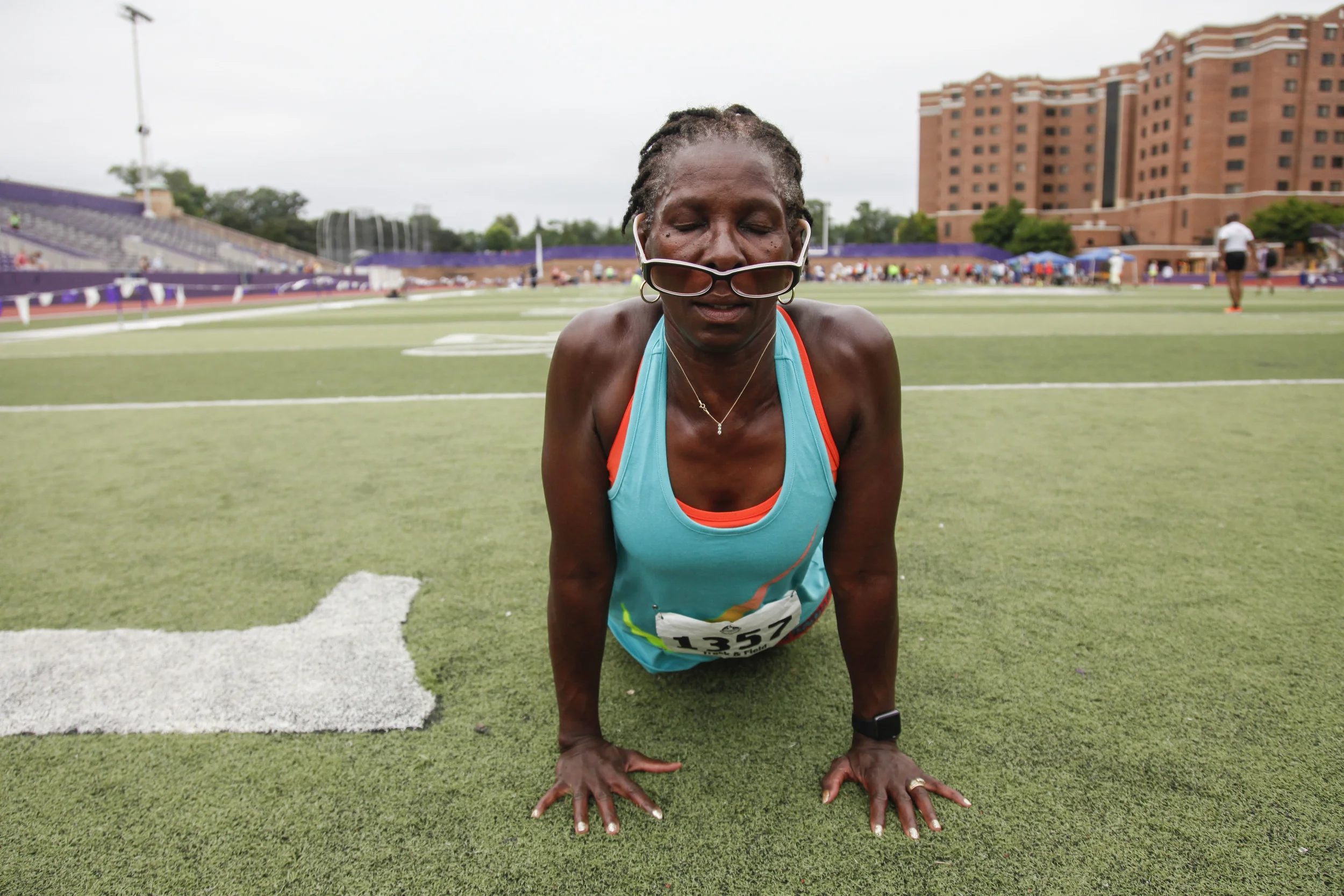 Regina Stewart, a runner participating in the 2015 National Senior Games Track and Field event, stretches in between heats on the St. Thomas University Field in Minneapolis, MN. This event took place on Jul. 14, 2015.