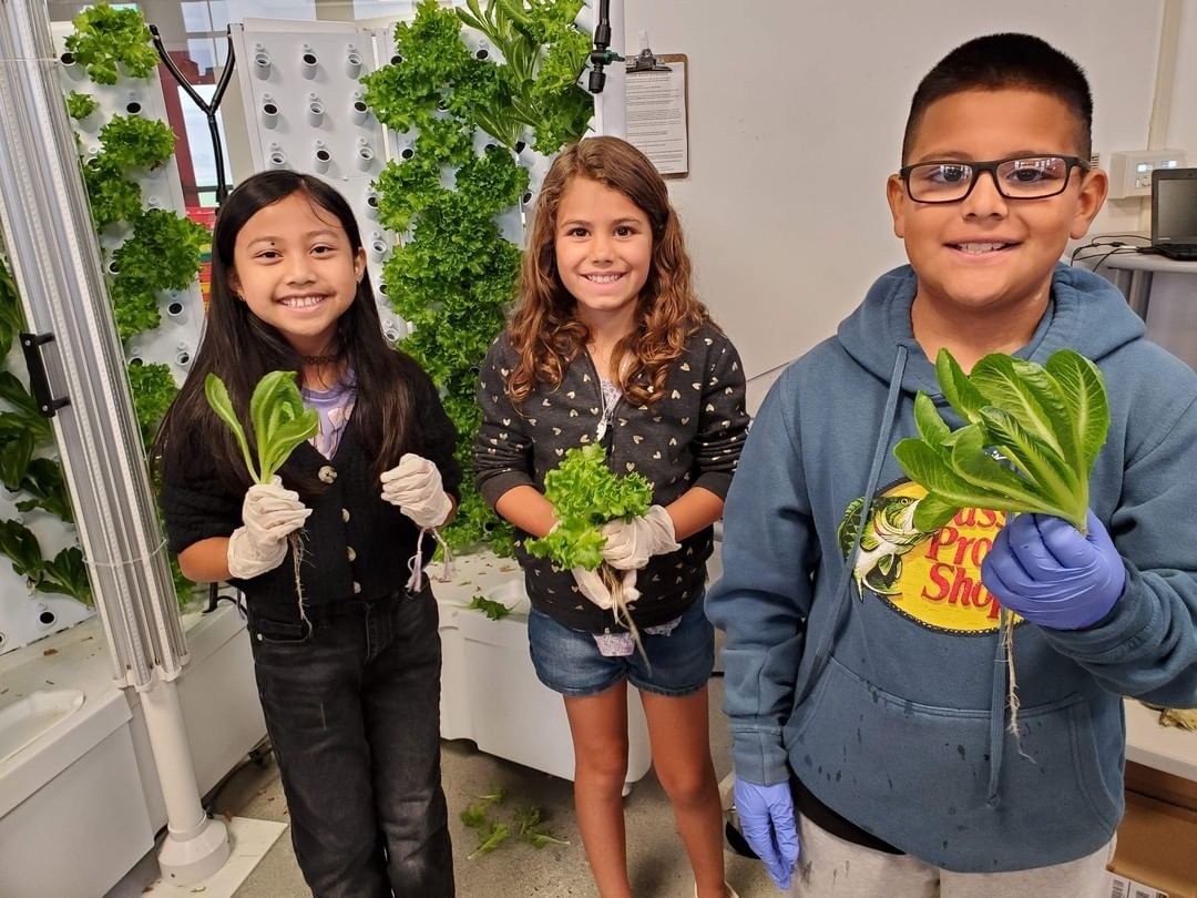 Three students with lettuce