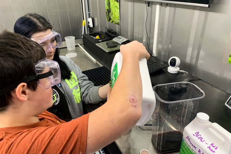 Two students measure hydroponic nutrients in agriculture class