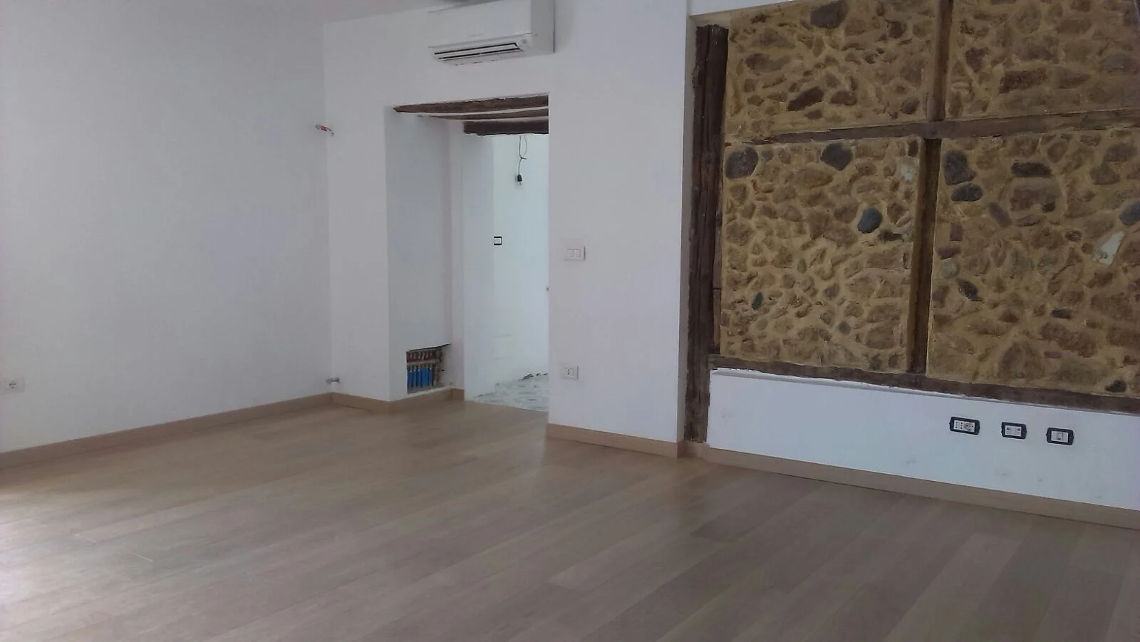 Dependance: living room with passage to the kitchen and restored original stone wall