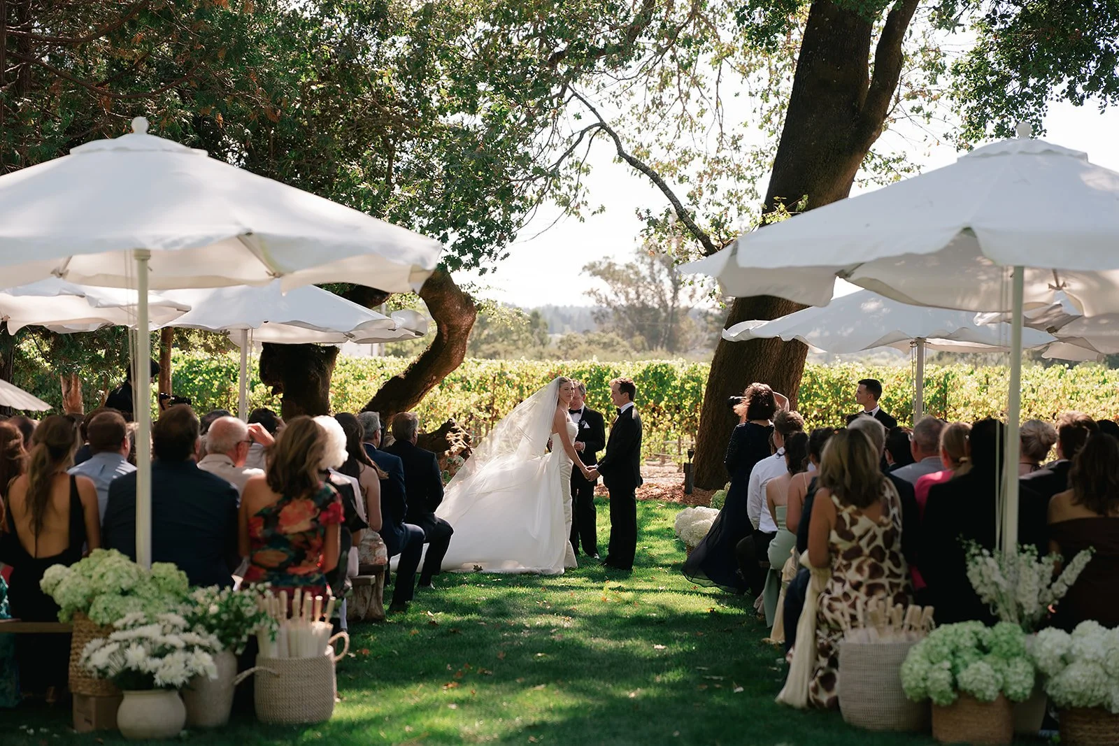 Outdoor wedding ceremony beneath oak trees at Oak Grove Estate in Sonoma County, with curated aisle decor by L’Relyea Events