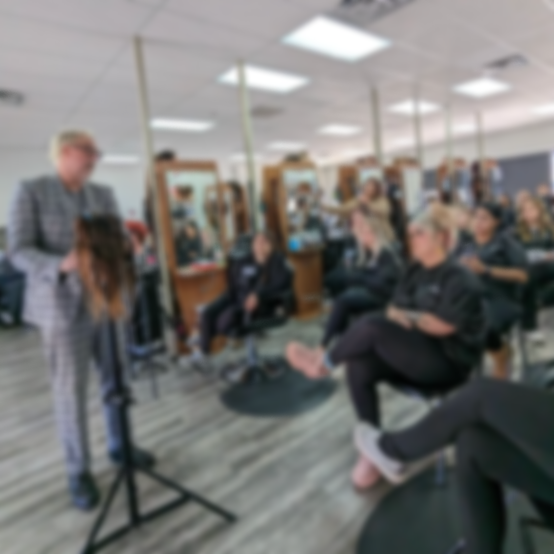 Women in a hair salon getting their hair styled, with hairstylist and mirrors in the background.