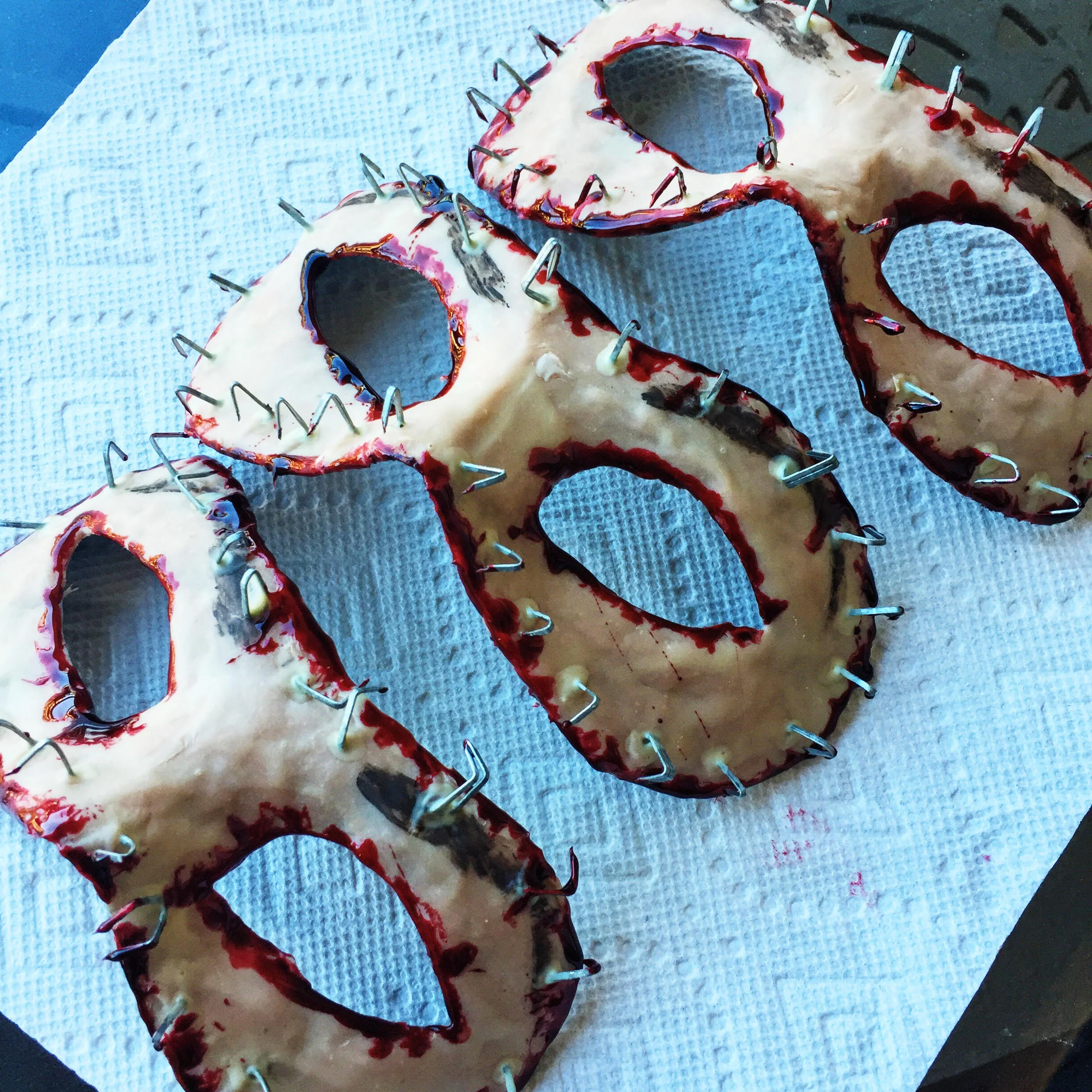 The masquerade flesh masks after applying scar wax, faux blood, and wood staples.