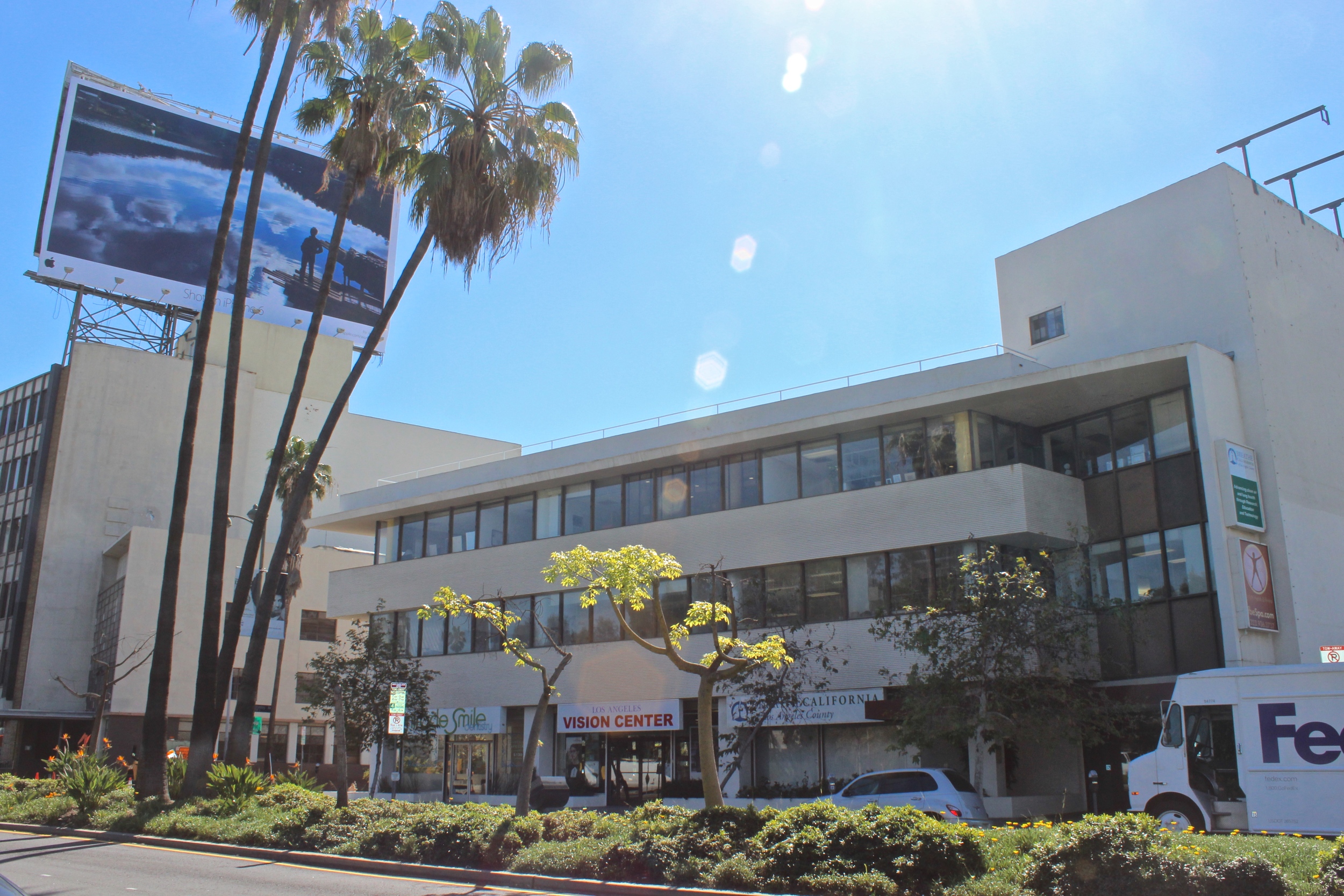 Three story off white mixed use building with retail shops on the first floor.