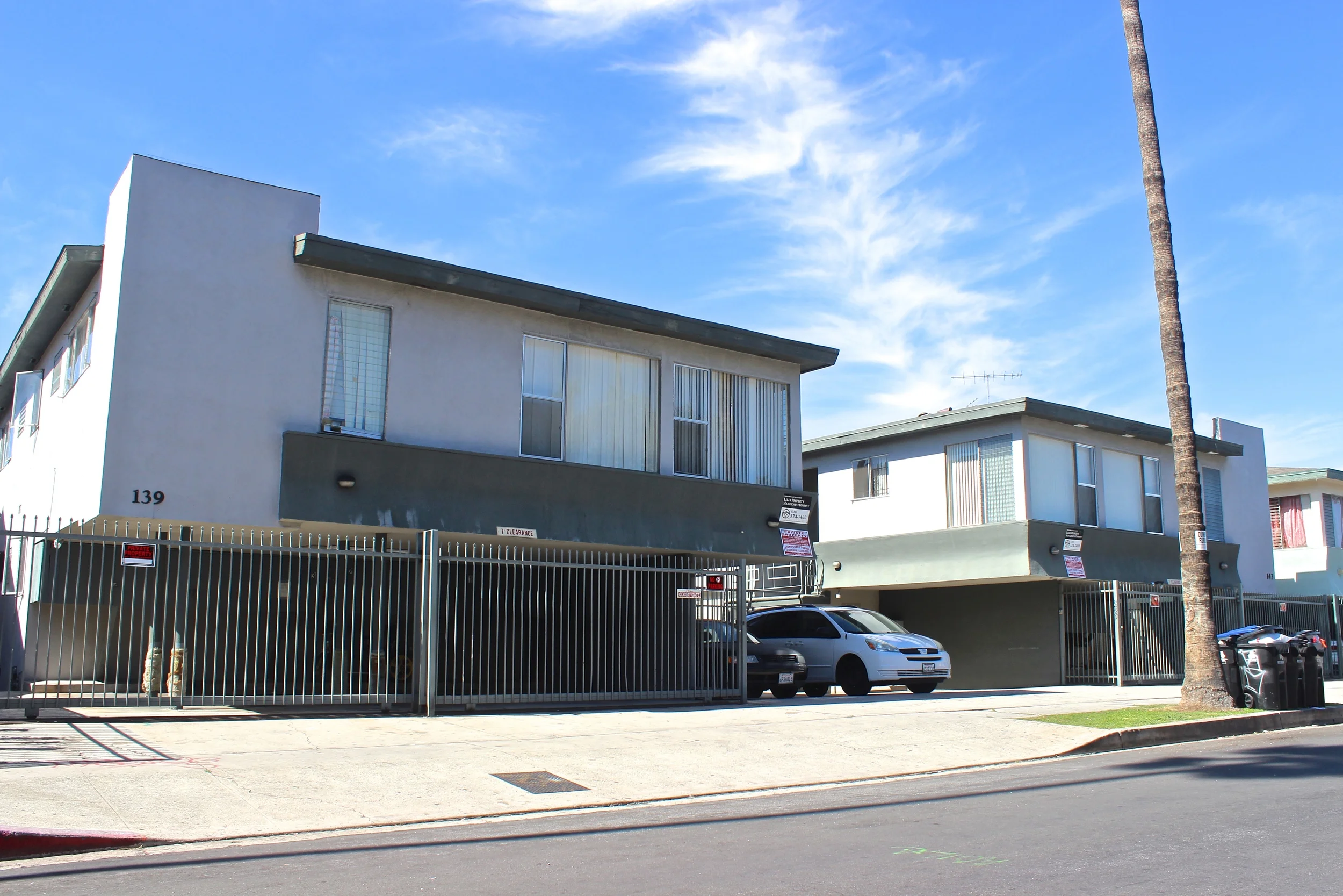 Grey and green apartment building with motorized gated garage.