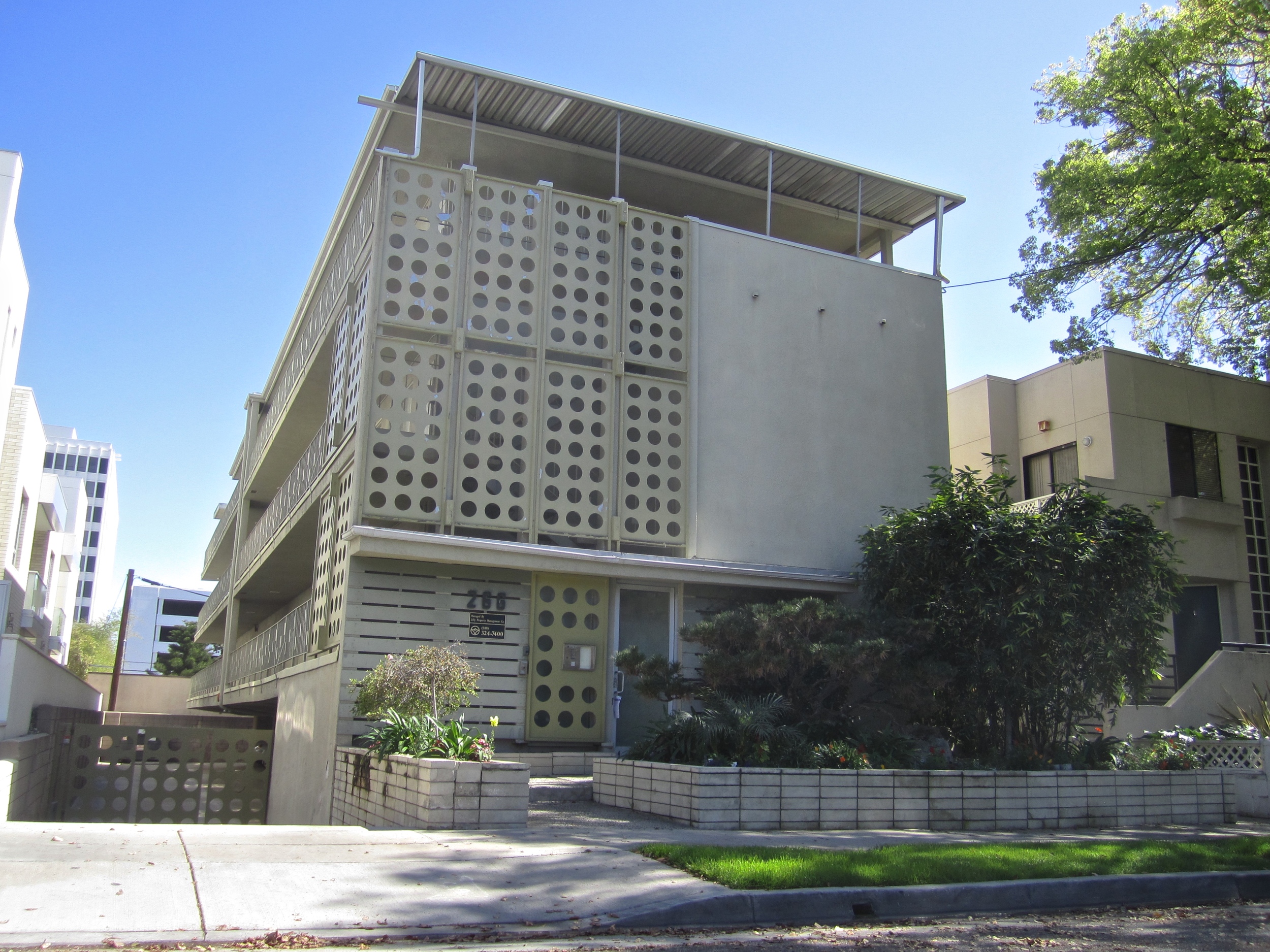 White apartment building with lattice facade  with gated parking.