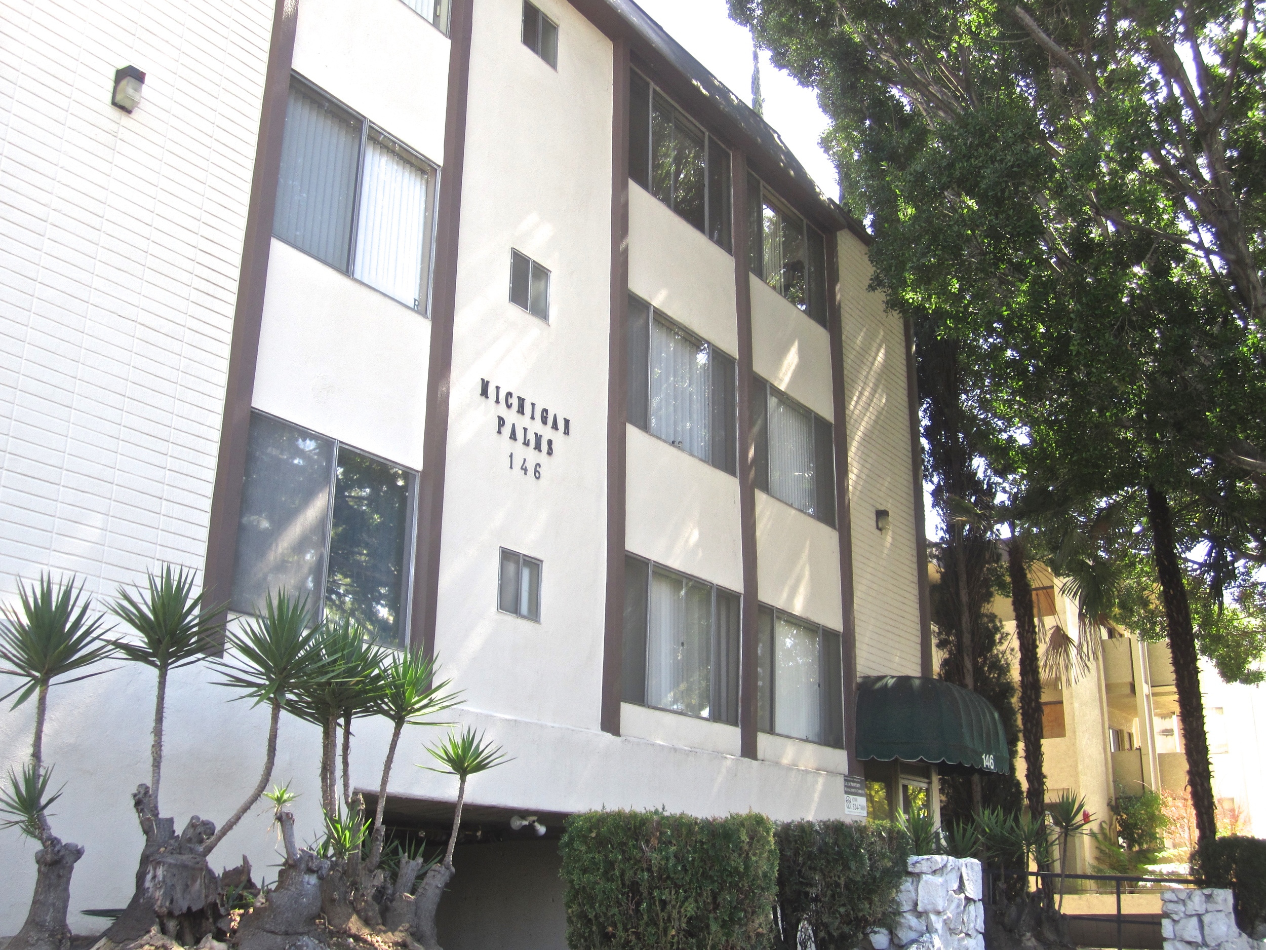 Off white three story apartment building with brown accents.