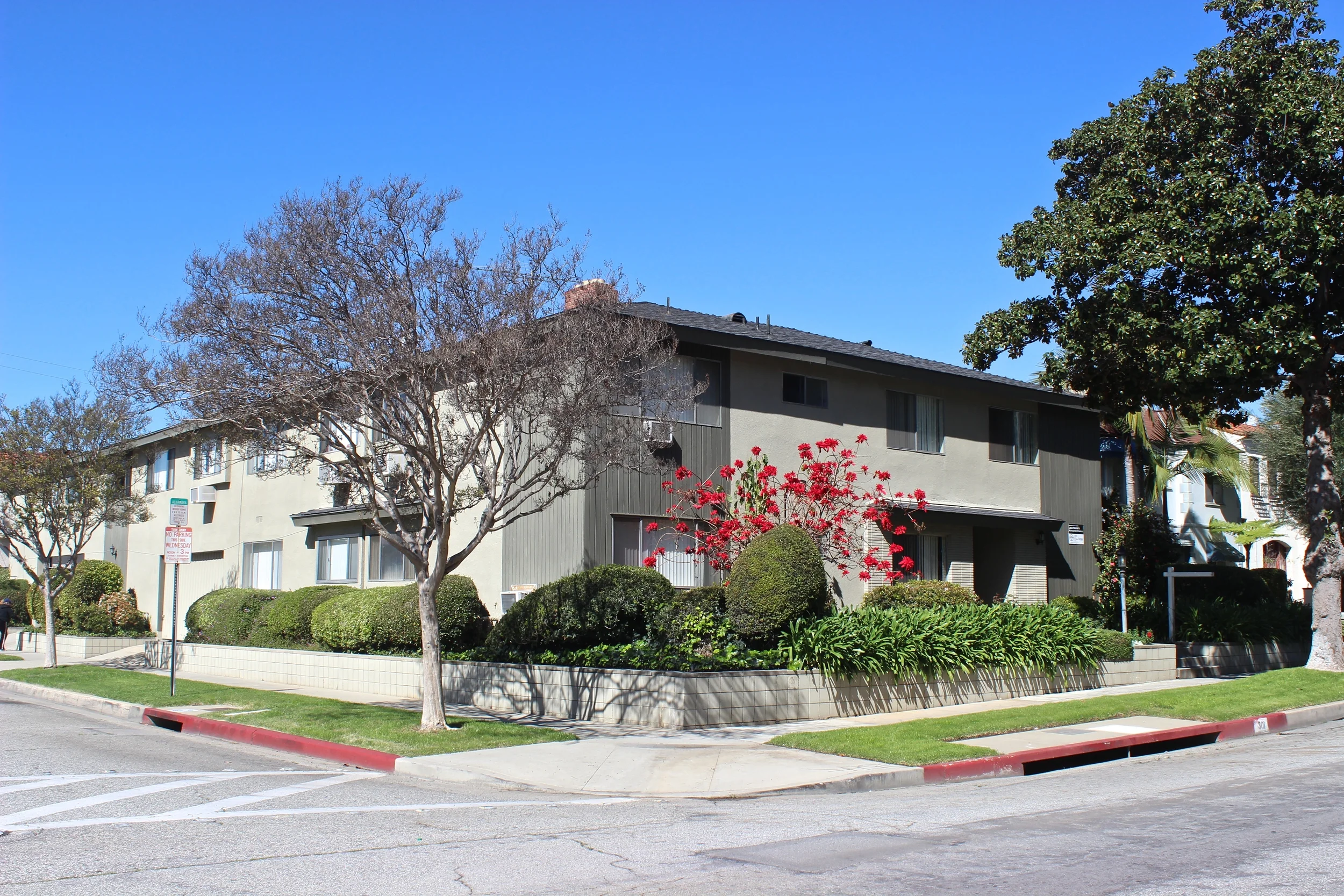  White and gray corner lot apartment building with black roofing.