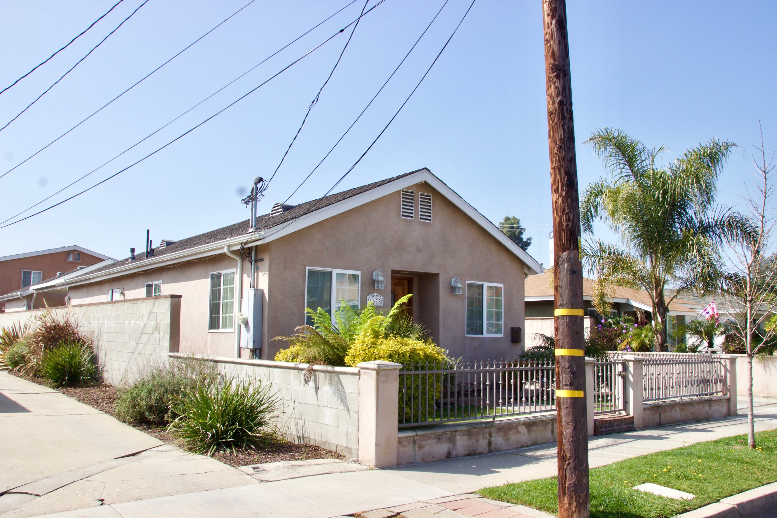 Cozy single-story house with front yard, bordered by a concrete fence.