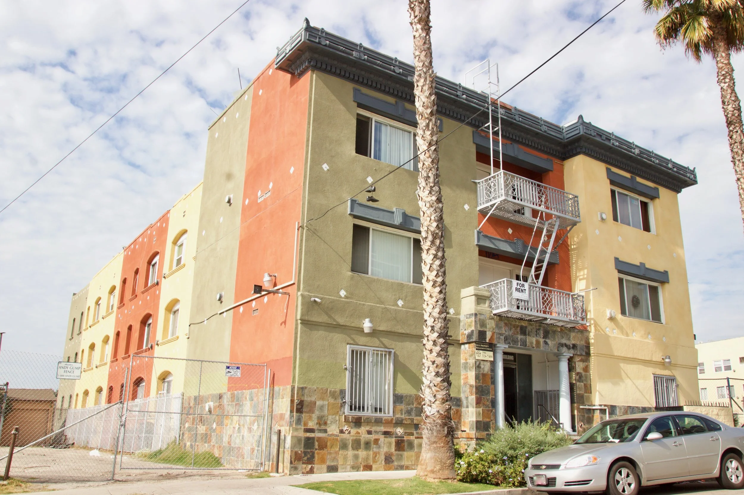 Green, yellow and red apartment building with a fire escape in the middle above the front door.
