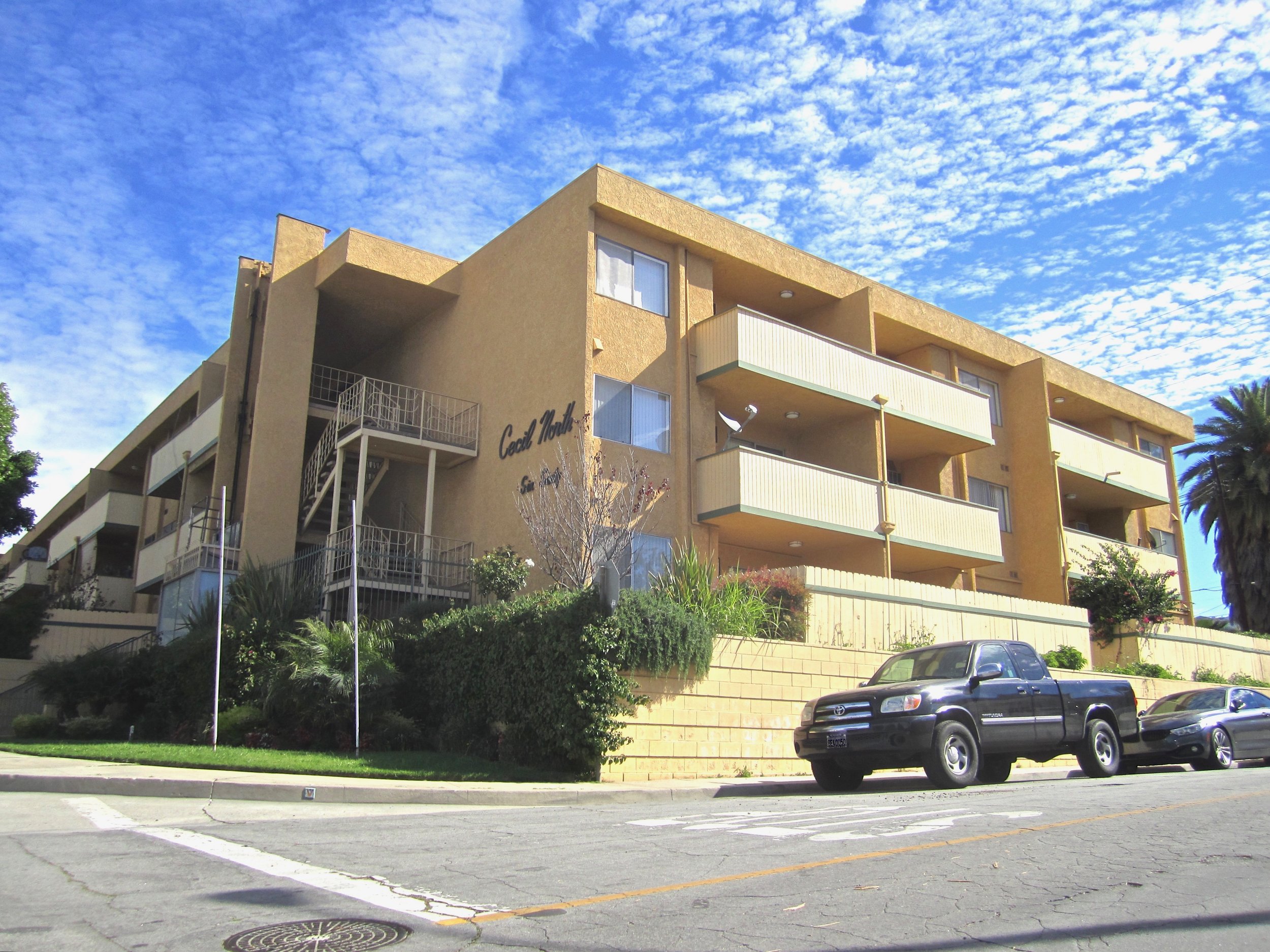 Brown apartment building located on a corner lot with balconies facing the street.