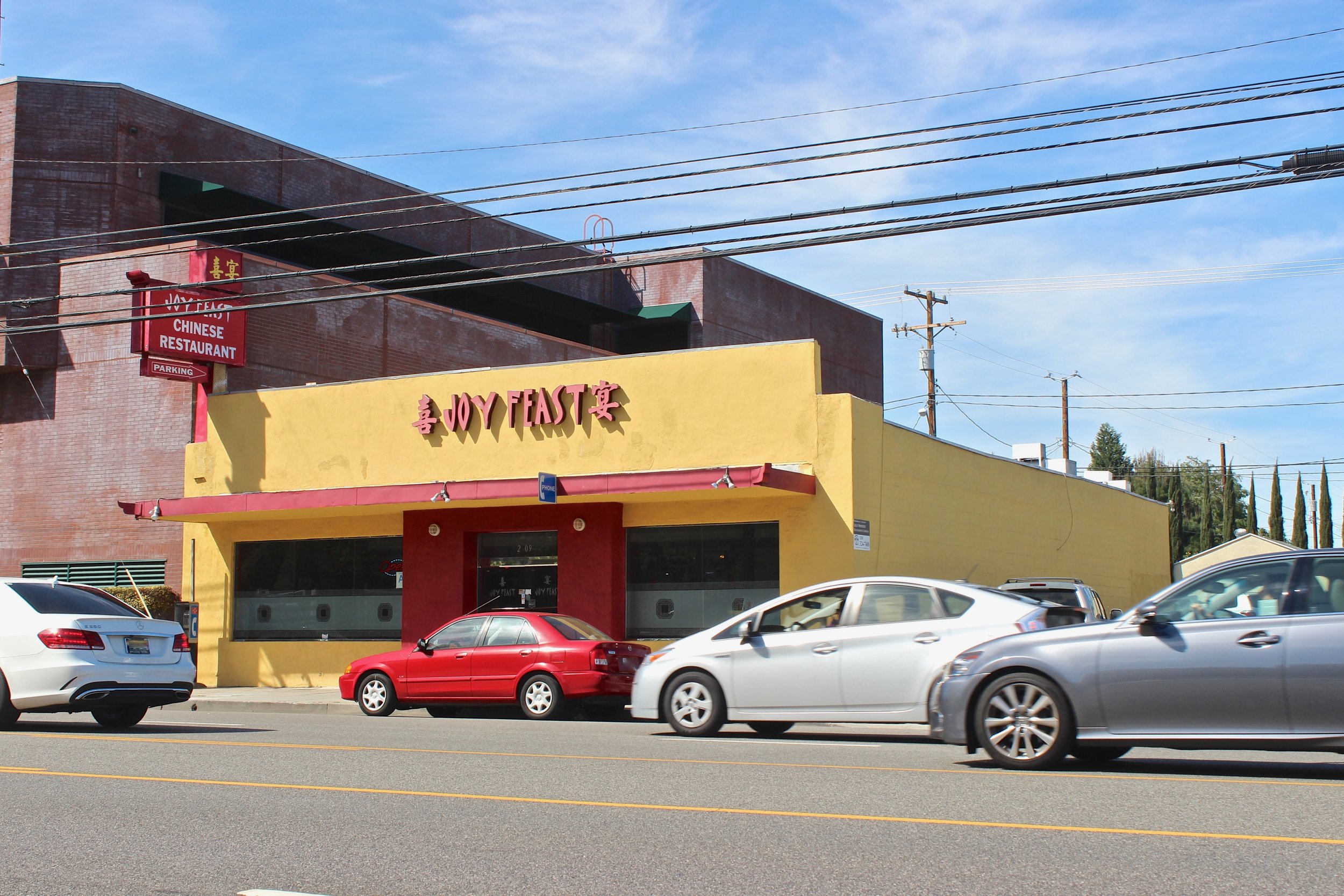 Street view of yellow building with Joy Feast sign in red lettering.