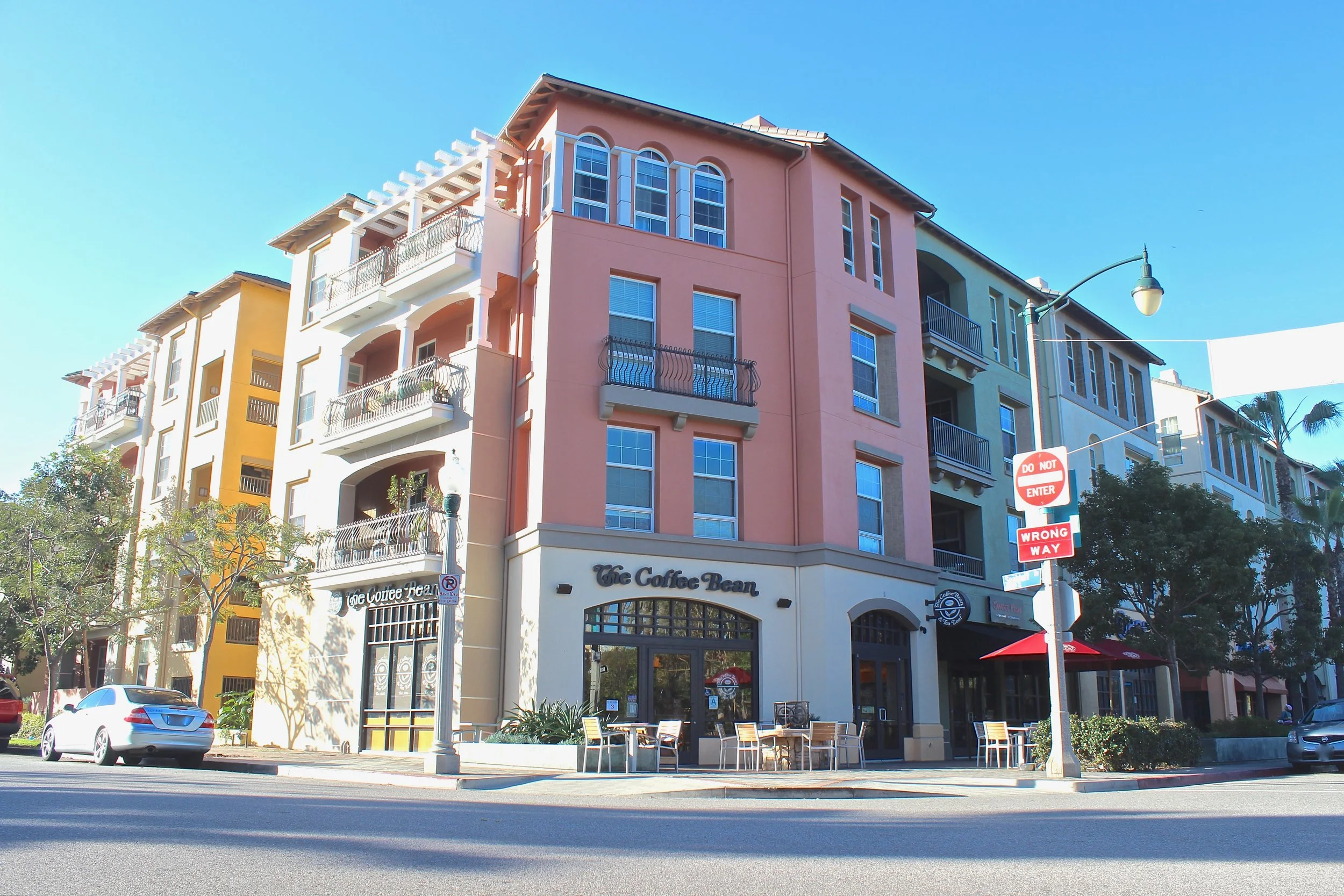 Four story Multi color apartment complex above The Coffee Bean on a main street.