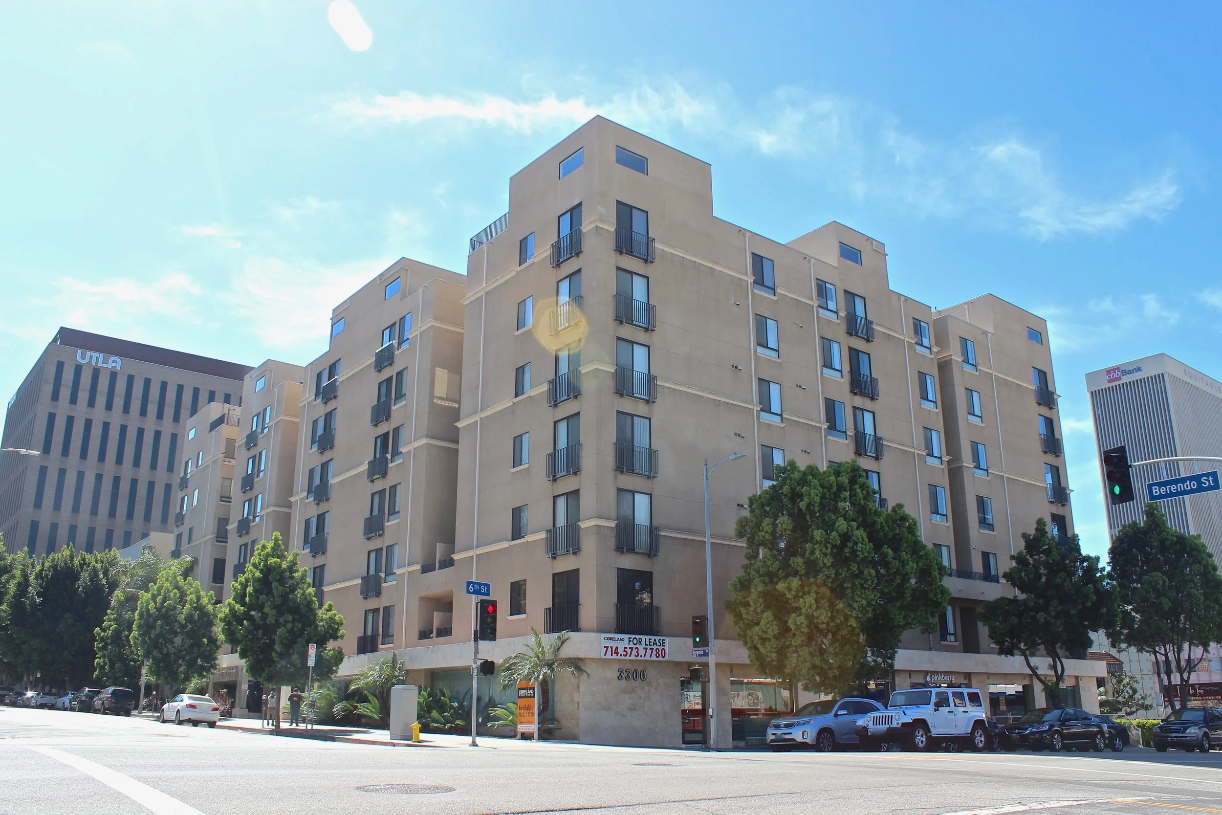 Taupe seven story condominium on the corner of a city street.