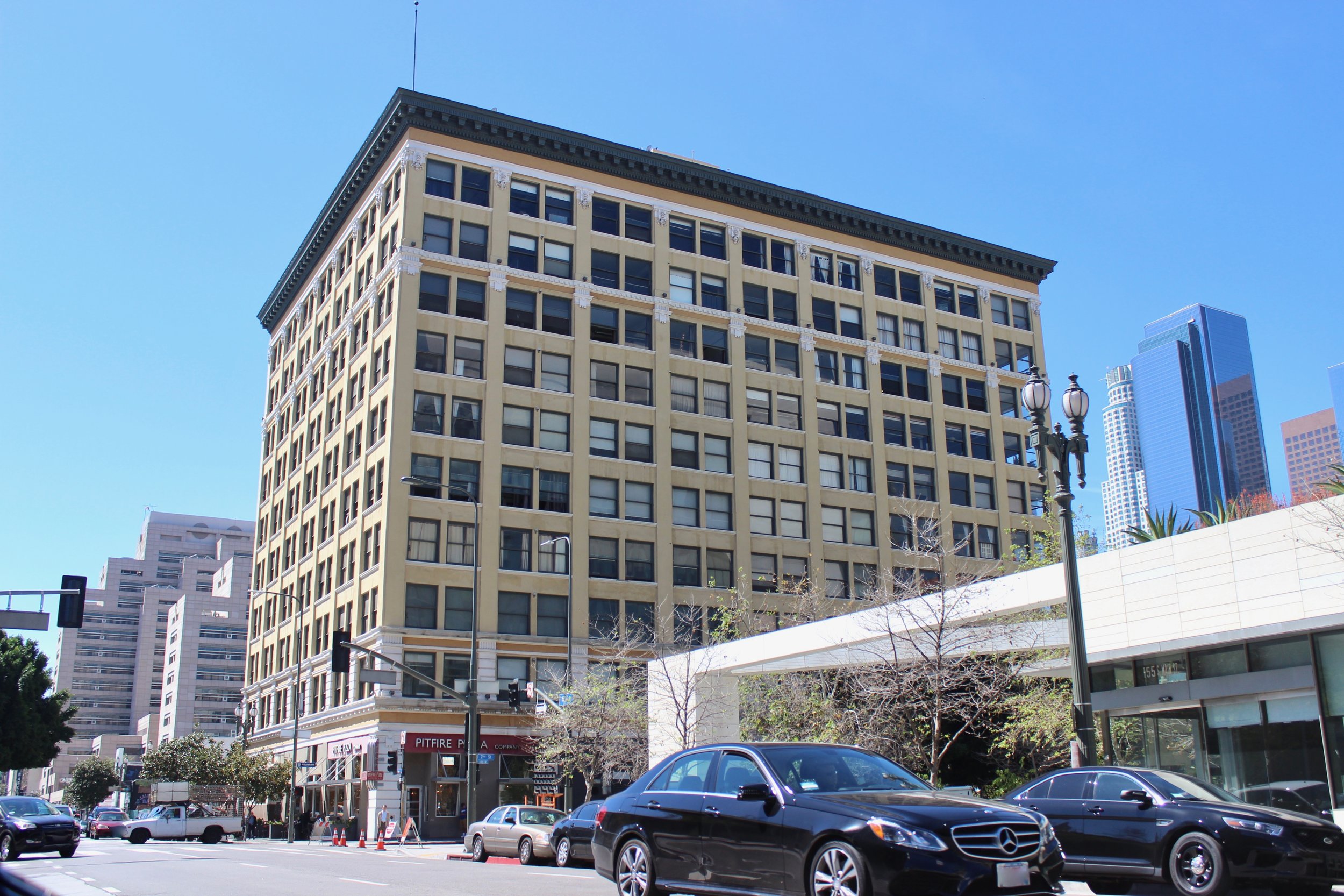  Corner lot ten story off white condominium on a busy city street.