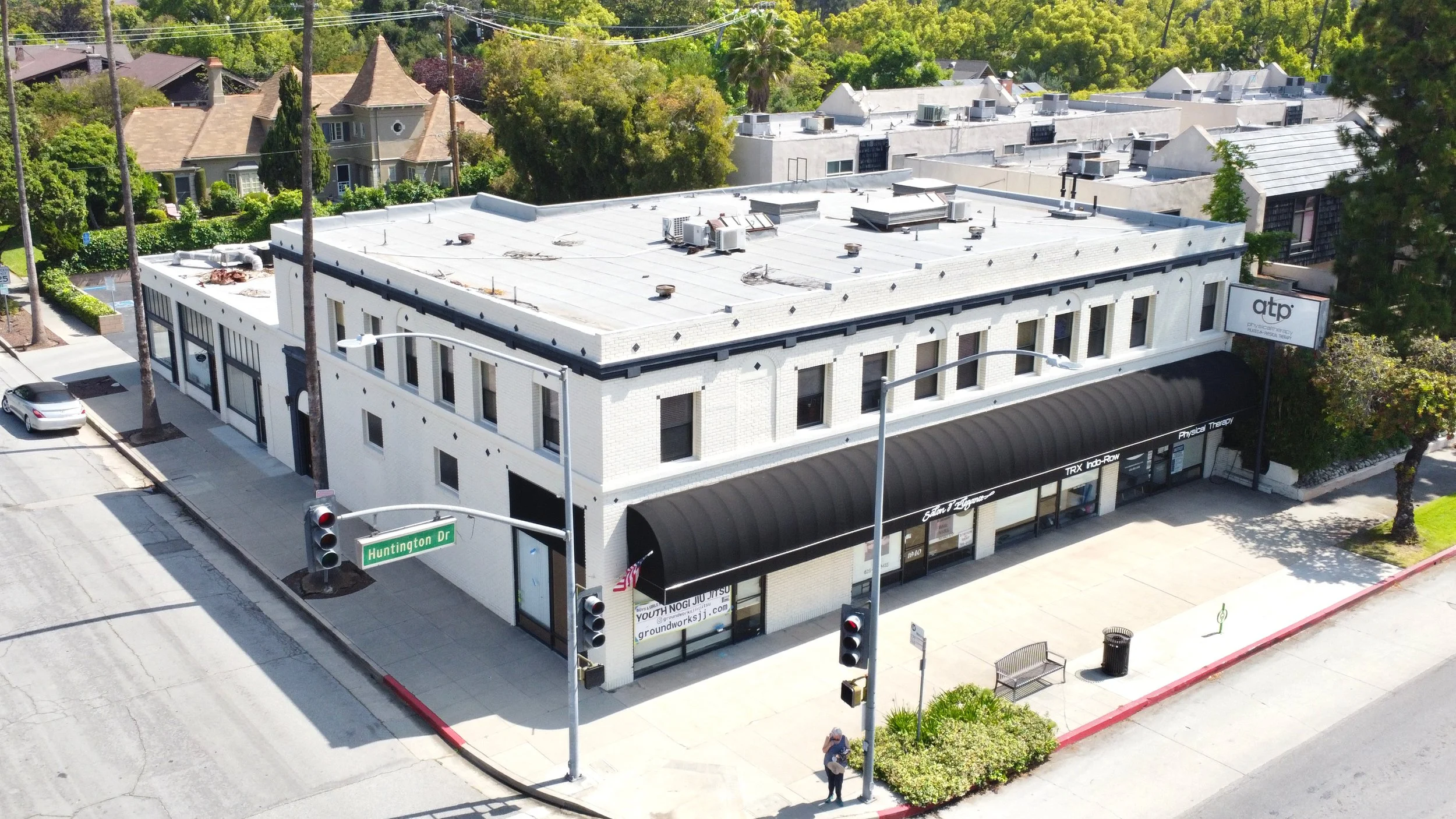 Corner lot white mixed use building with black canopy over retail stores.