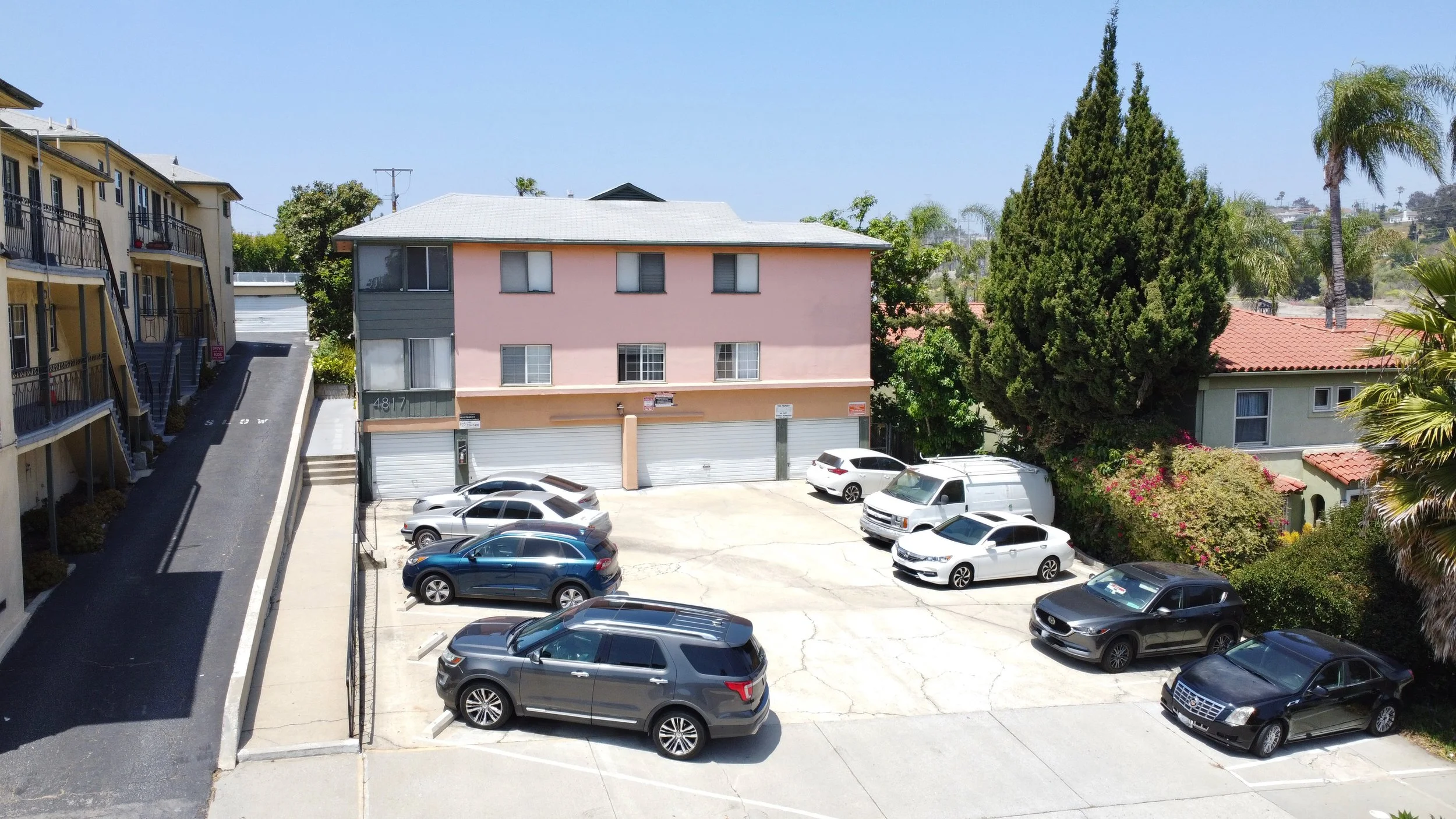 Aerial shot of peach apartment building with spacious parking area.