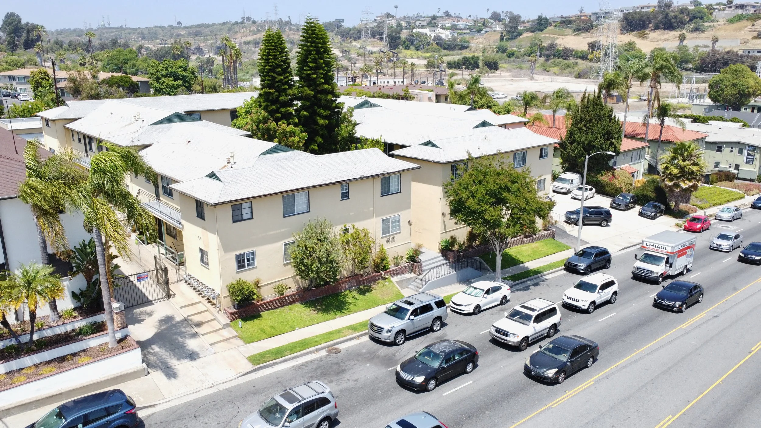 Aerial view of yellow apartment complex by a busy street.