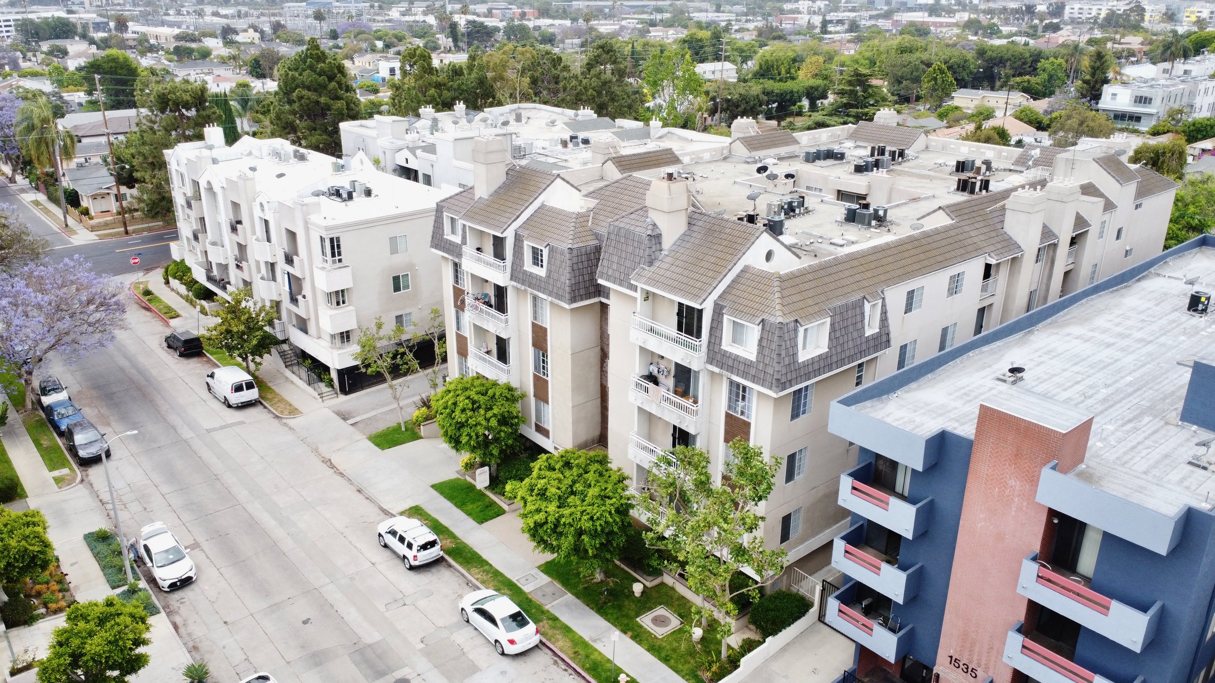 Overcast aerial shot of modern townhomes flanking a quiet street. 