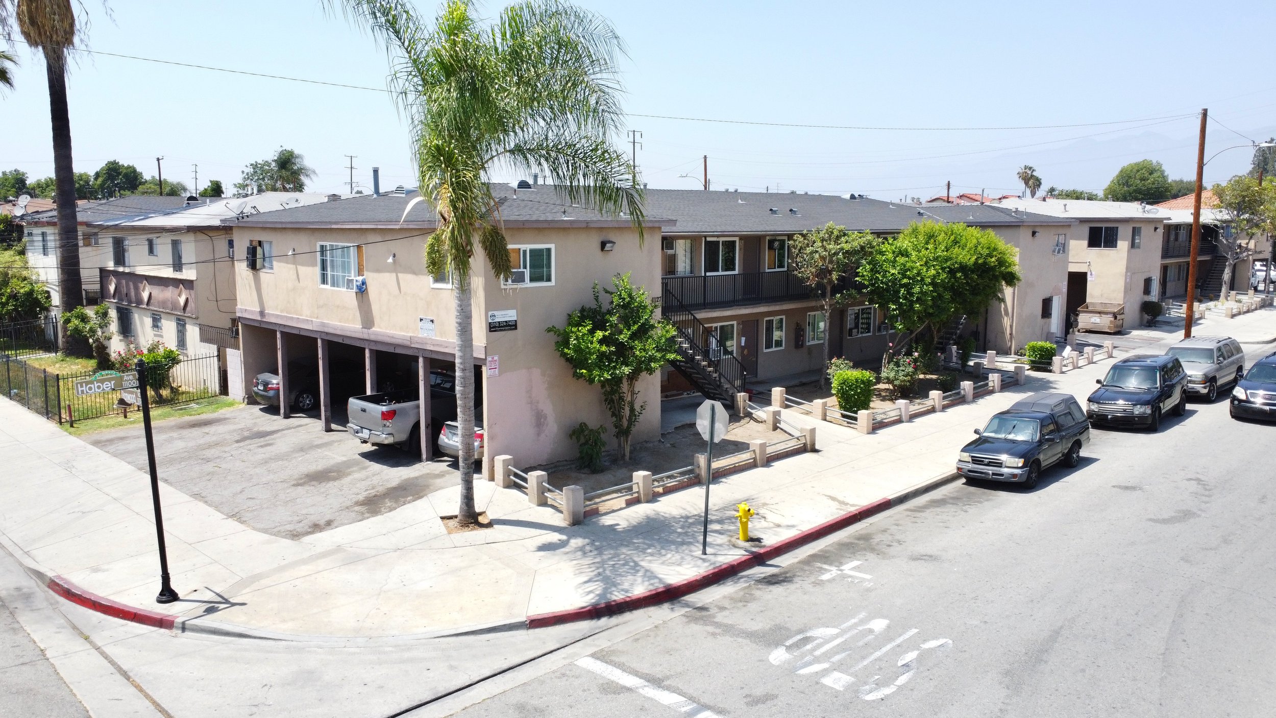 Corner lot, off white apartment building with gray roof. Street and airport parking.