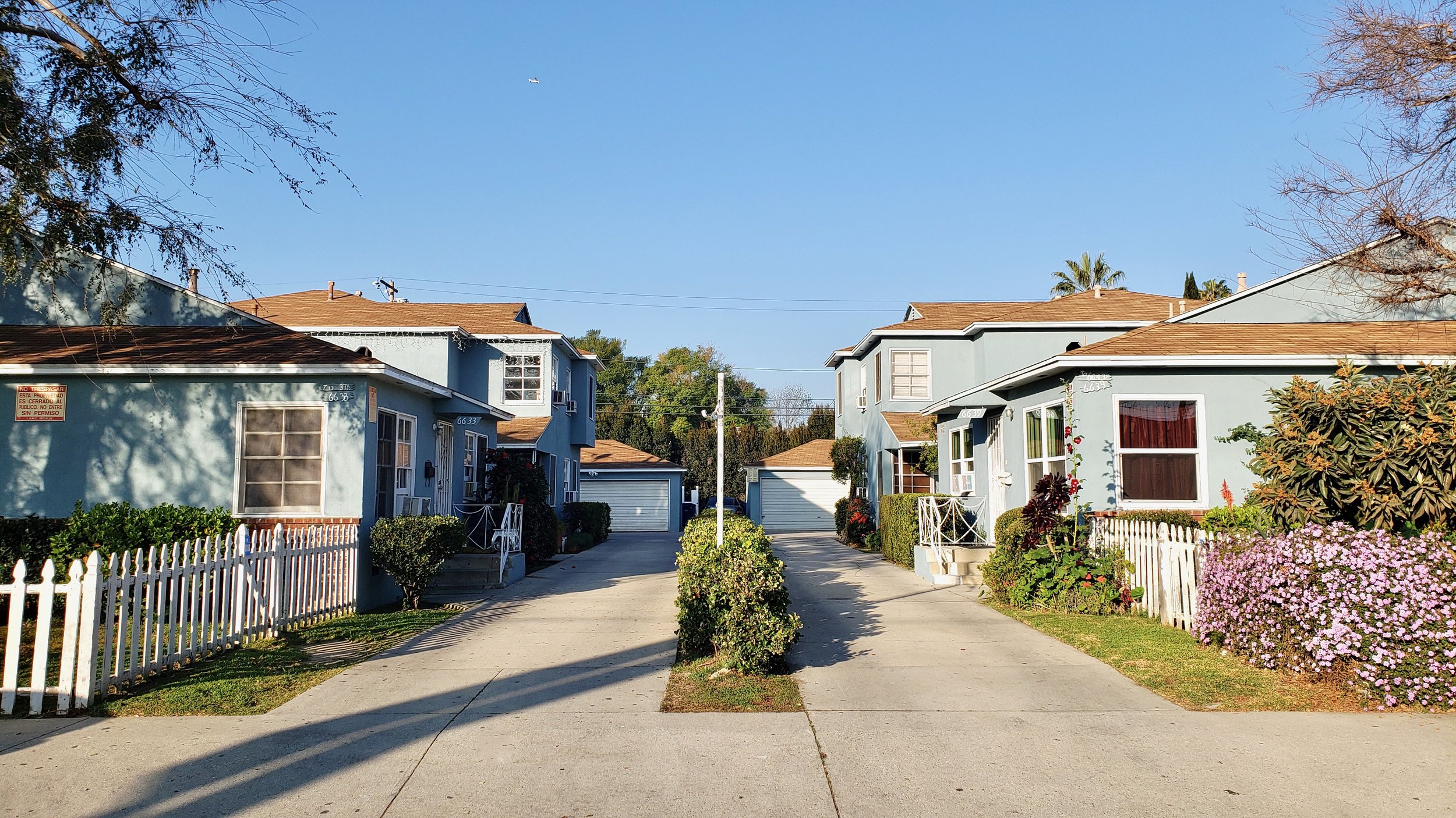 Two blue housing complexes with driveways leading  to and from garages located at the rear of the buildings.