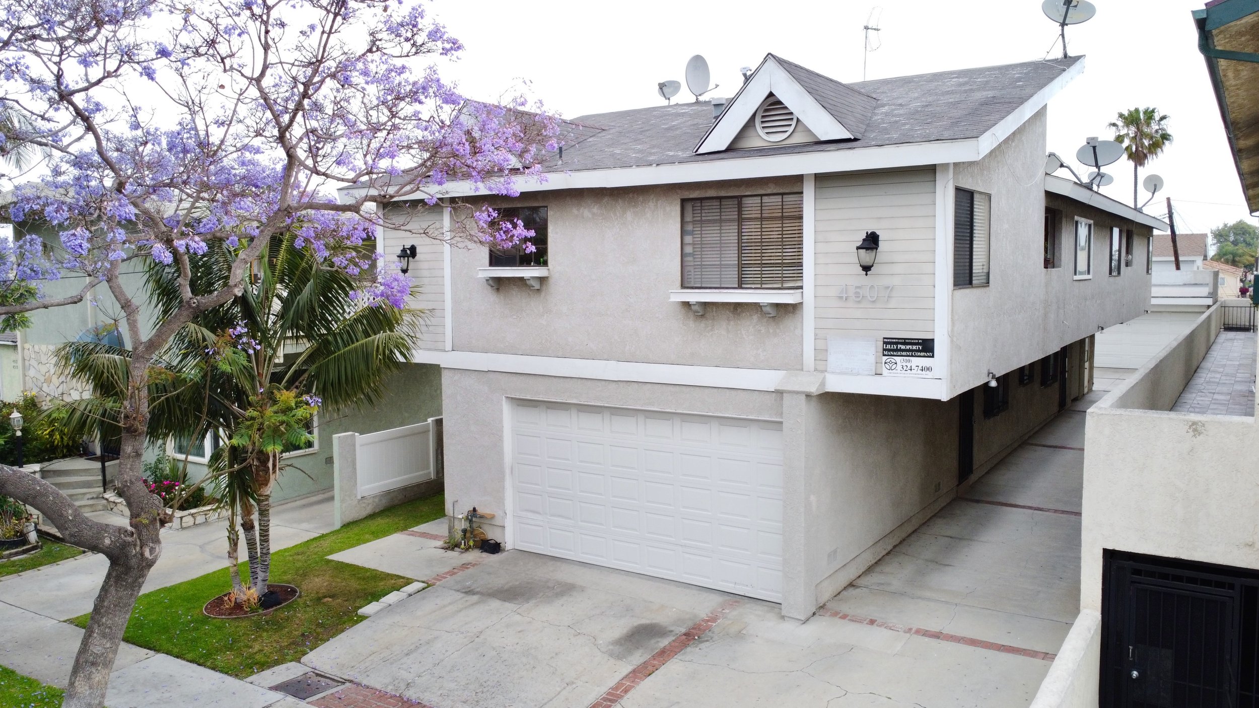 House with white garage and purple-flowered tree.