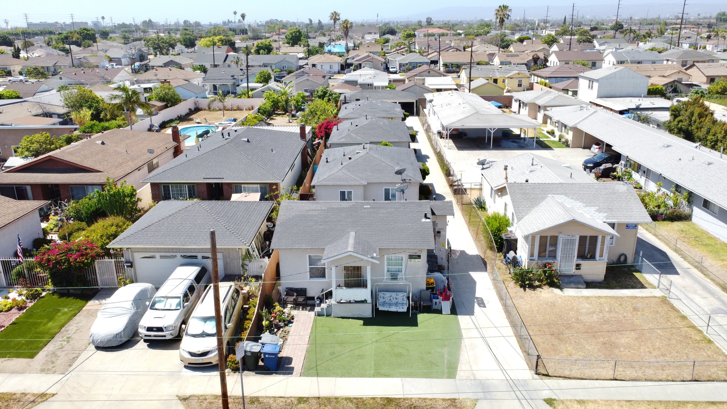 Bird’s-eye view of a suburban street with houses, lawns, and cars.