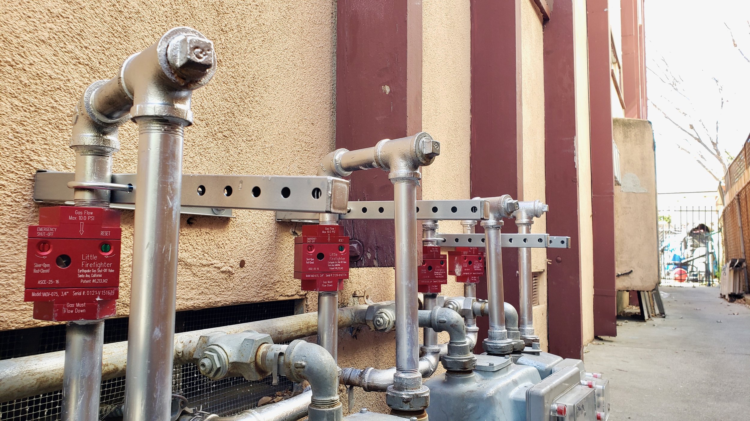 Gas meters and emergency shutoff valves on a building's exterior wall.