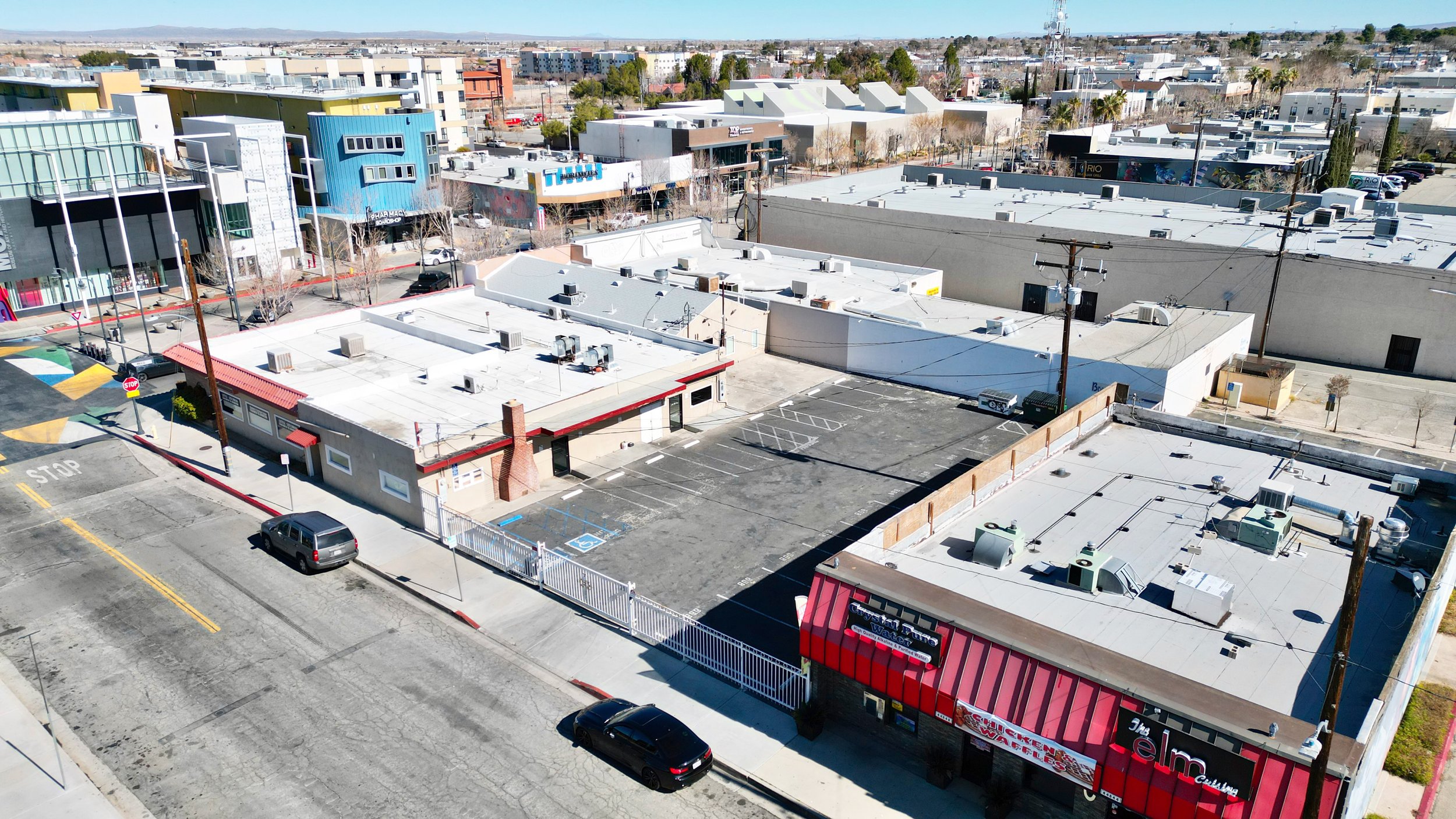 Aerial view of red eatery, cars, streets, with residential backdrop under clear skies.