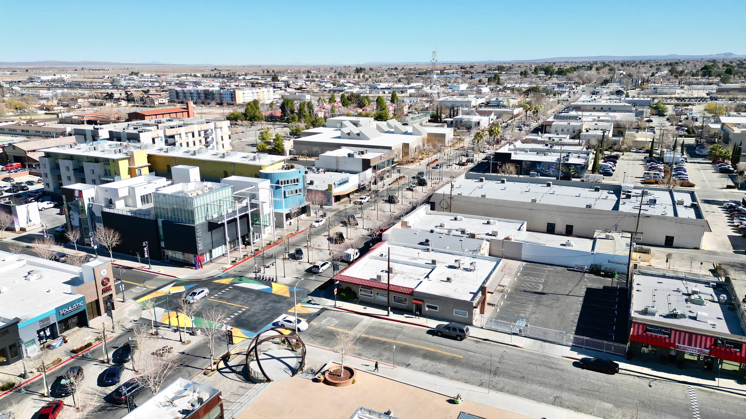 Overhead view of a street corner with colorful buildings and a desert backdrop.