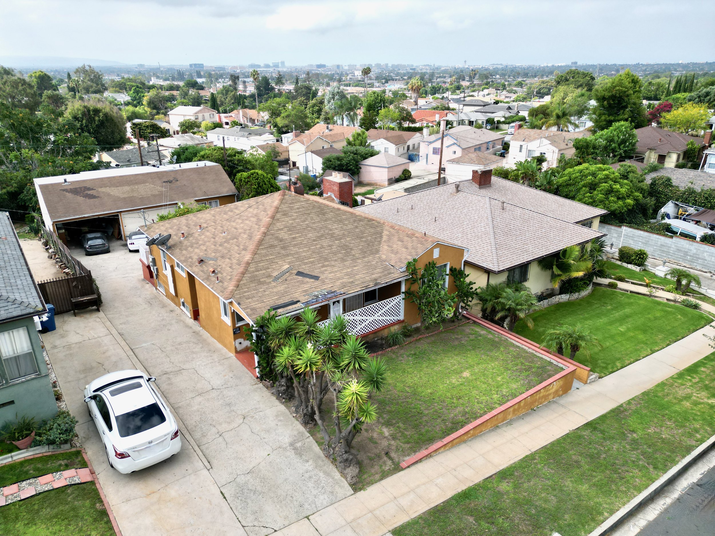 Elevated view of orange house with green lawn and tall palms.