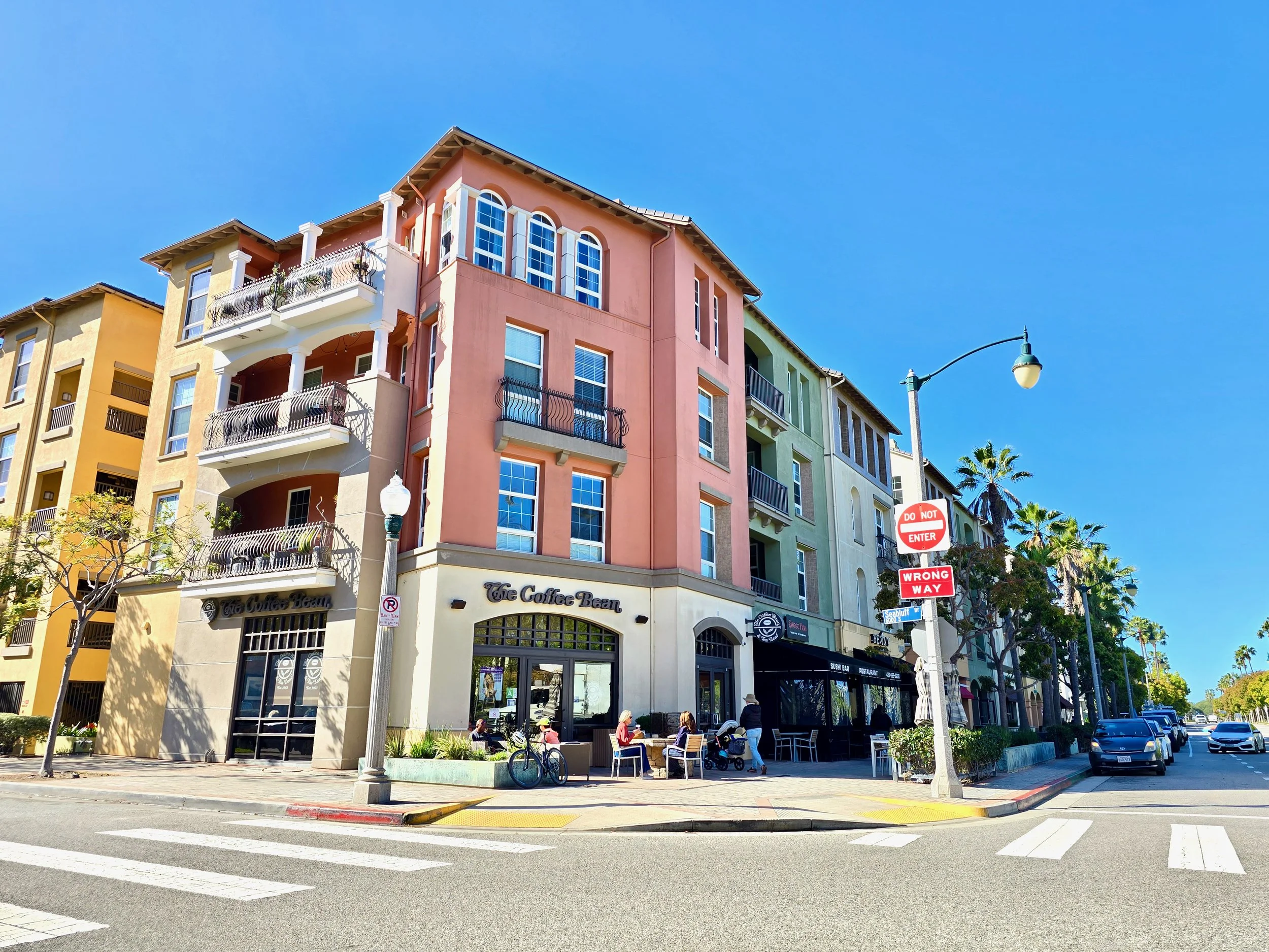View 13020 Pacific Promenade surround a bustling coffee shop with outdoor seating, under a clear blue sky in a vibrant urban setting.