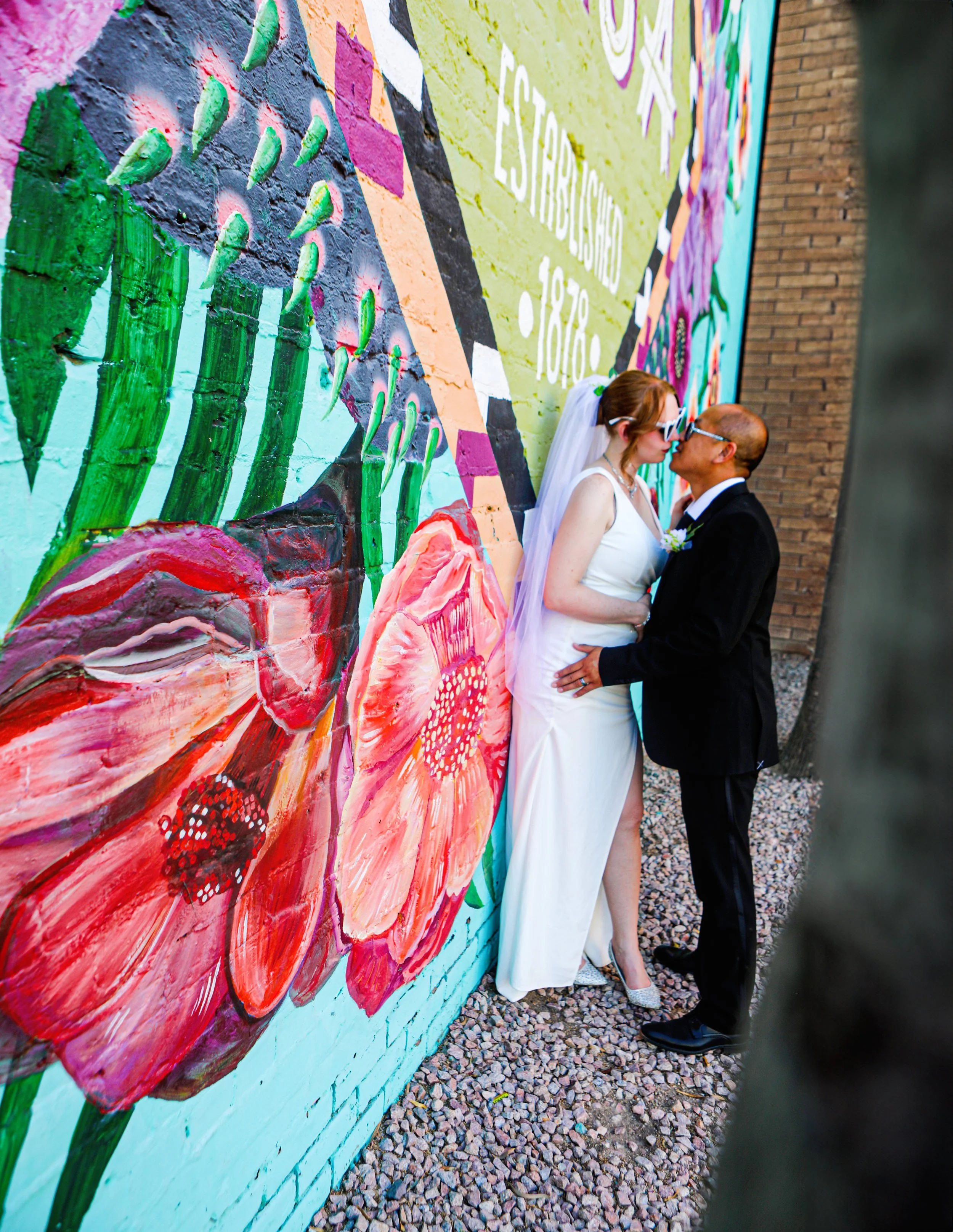 Rana and Nick during their intimate elopement in Mesa, Arizona, photographed by TallulahMade Photography. This romantic wedding portrait captures the couple celebrating their marriage against the warm desert architecture of Mesa, blending candid conn