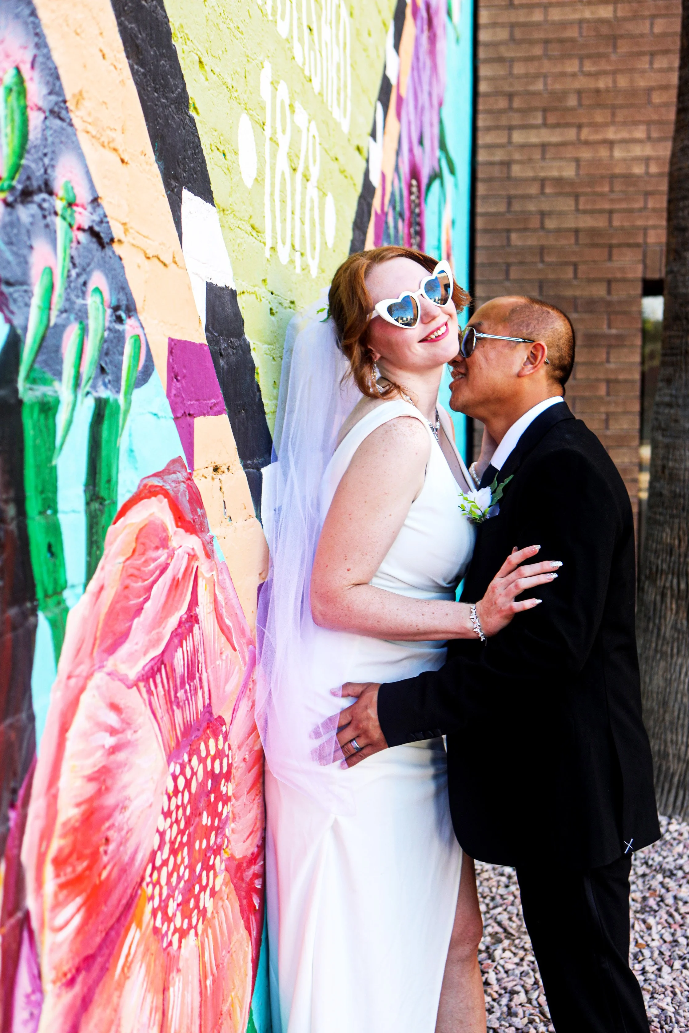 Rana and Nick during their intimate elopement in Mesa, Arizona, photographed by TallulahMade Photography. This romantic wedding portrait captures the couple celebrating their marriage against the warm desert architecture of Mesa, blending candid conn
