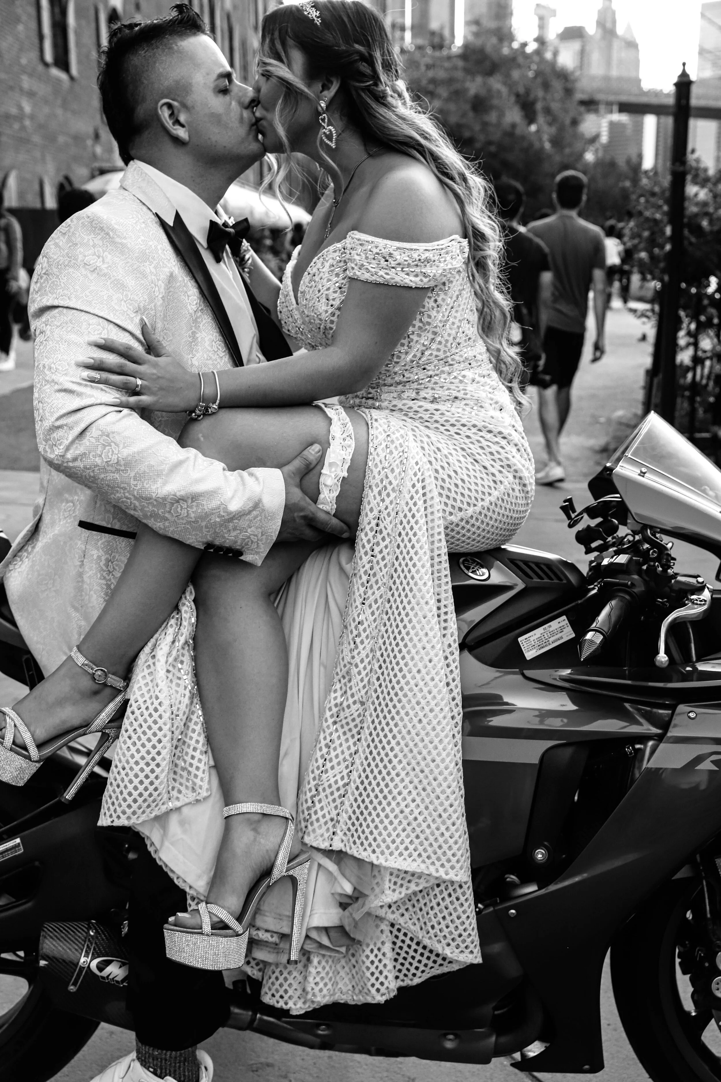 Black and white wedding portrait of a newlywed couple embracing beside a motorcycle, photographed by TallulahMade.