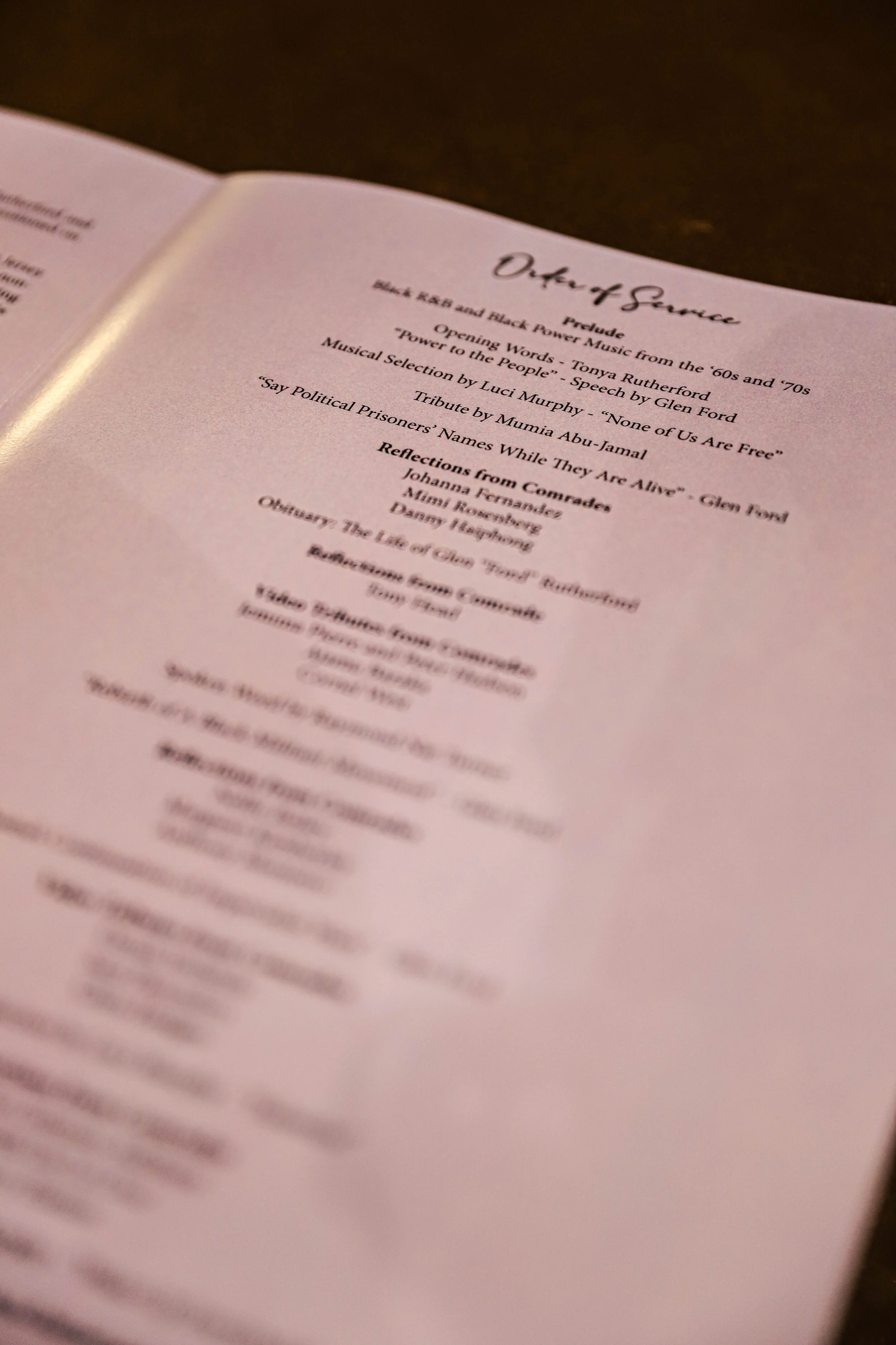Close-up of a printed program or booklet page titled 'Ode of Silence', listing songs and reflections, with a dark background.