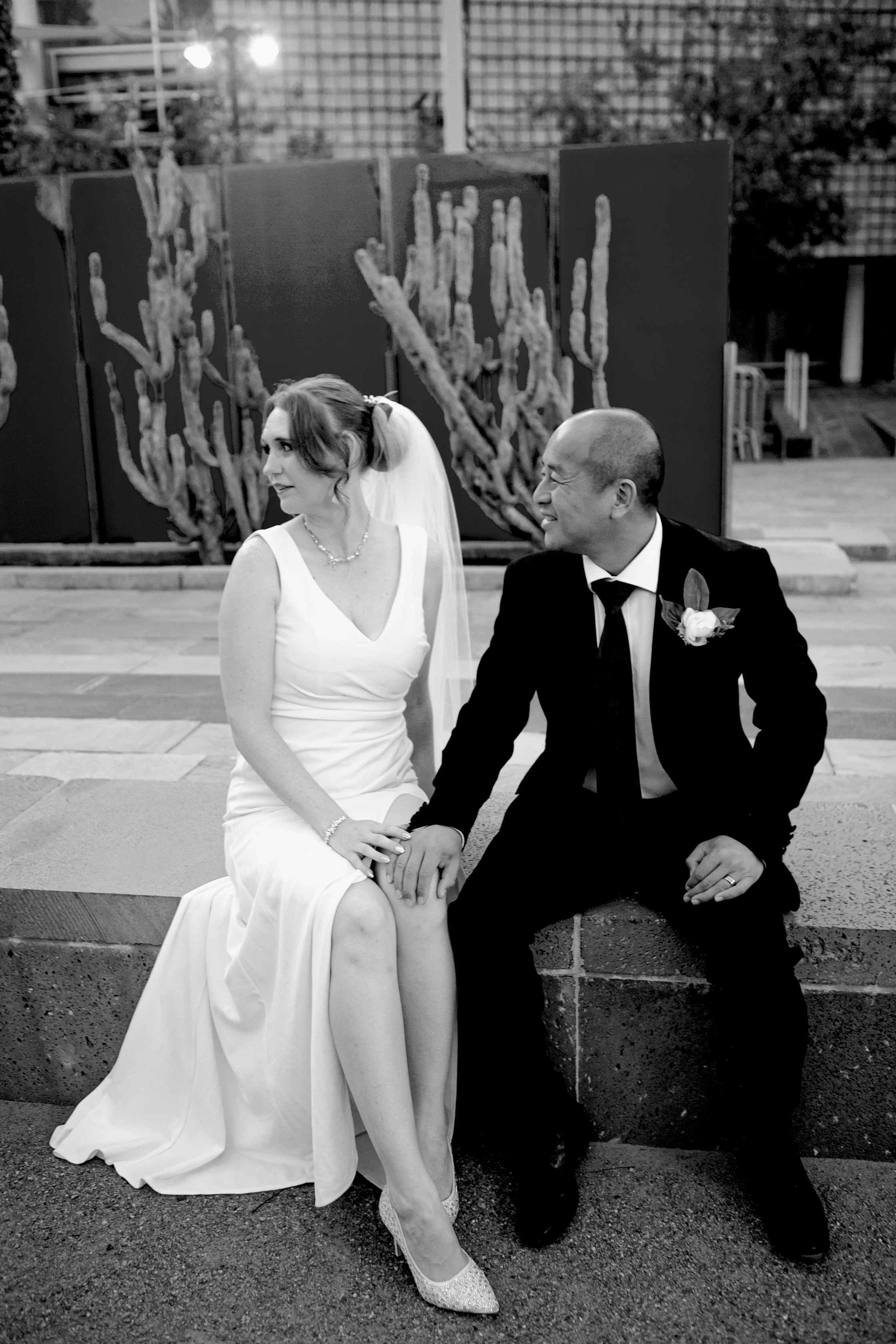 Rana and Nick during their intimate elopement in Mesa, Arizona, photographed by TallulahMade Photography. This romantic wedding portrait captures the couple celebrating their marriage against the warm desert architecture of Mesa, blending candid conn