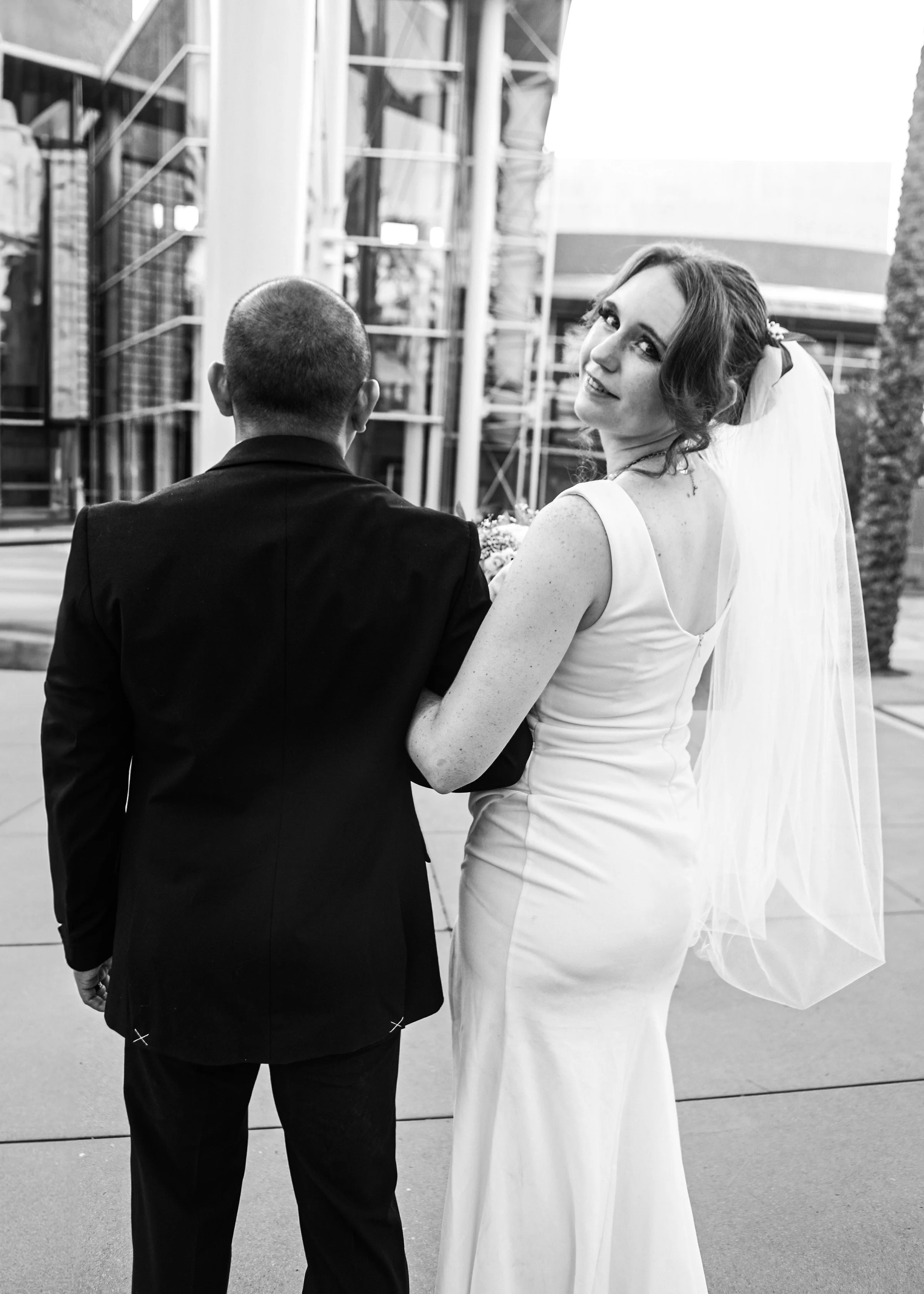 Rana and Nick during their intimate elopement in Mesa, Arizona, photographed by TallulahMade Photography. This romantic wedding portrait captures the couple celebrating their marriage against the warm desert architecture of Mesa, blending candid conn