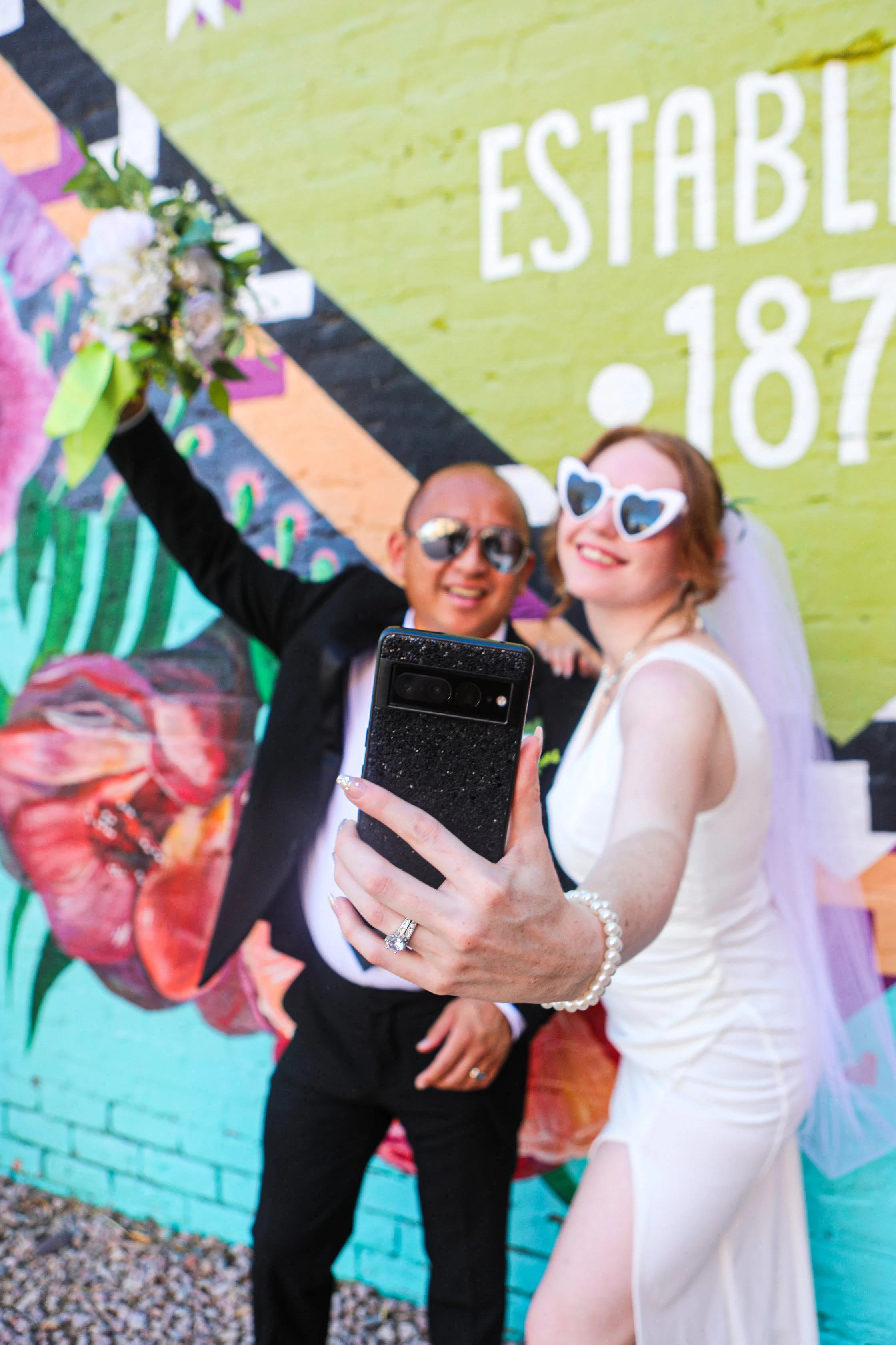 Rana and Nick during their intimate elopement in Mesa, Arizona, photographed by TallulahMade Photography. This romantic wedding portrait captures the couple celebrating their marriage against the warm desert architecture of Mesa, blending candid conn