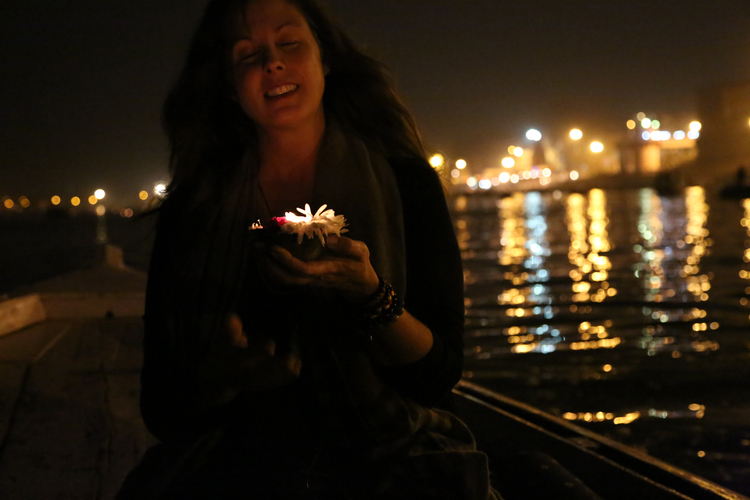 Michelle Larson - I feel most ALIVE when I am immersed in a foreign place; absorbing the energy, witnessing the devotion, experiencing the culture in a meaningful way. This photo was taken of me in Varanasi, India. I was in a row boat on the sacred Ganges River. The candle and flowers are an offering to the Gods; a wish or a prayer. I was mid-wish as this photo was taken... then I placed the candle in the water and watched it float to meet the hundreds of other flames, with their reflections dancing while they manifested.