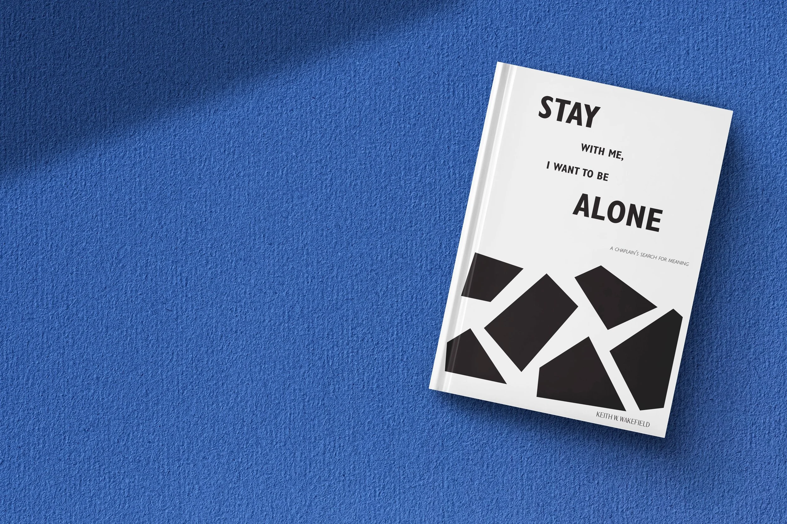 A book titled 'Stay with me, I want to be alone' by Keith W. Wakefield on a textured blue surface.