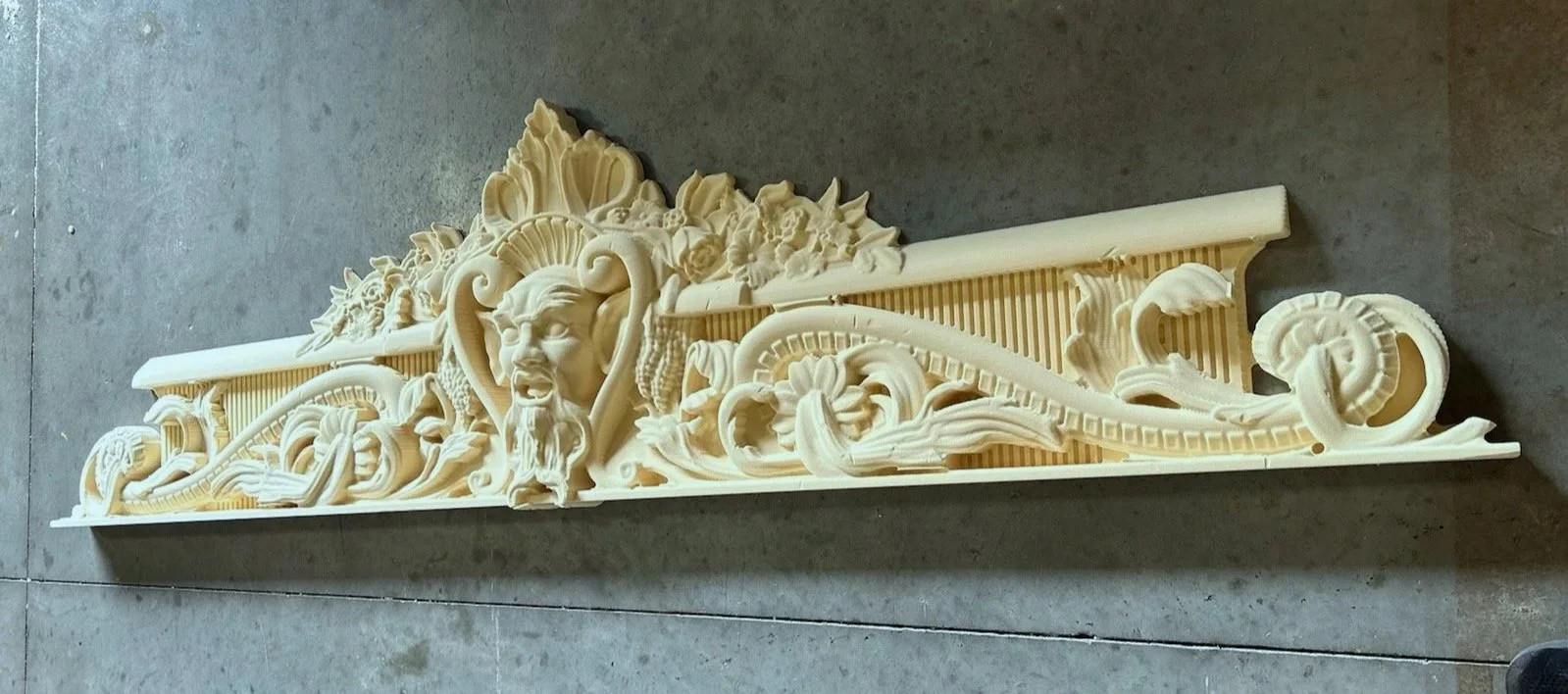 Intricate carved architectural ornament with a face, floral designs, and scrollwork.