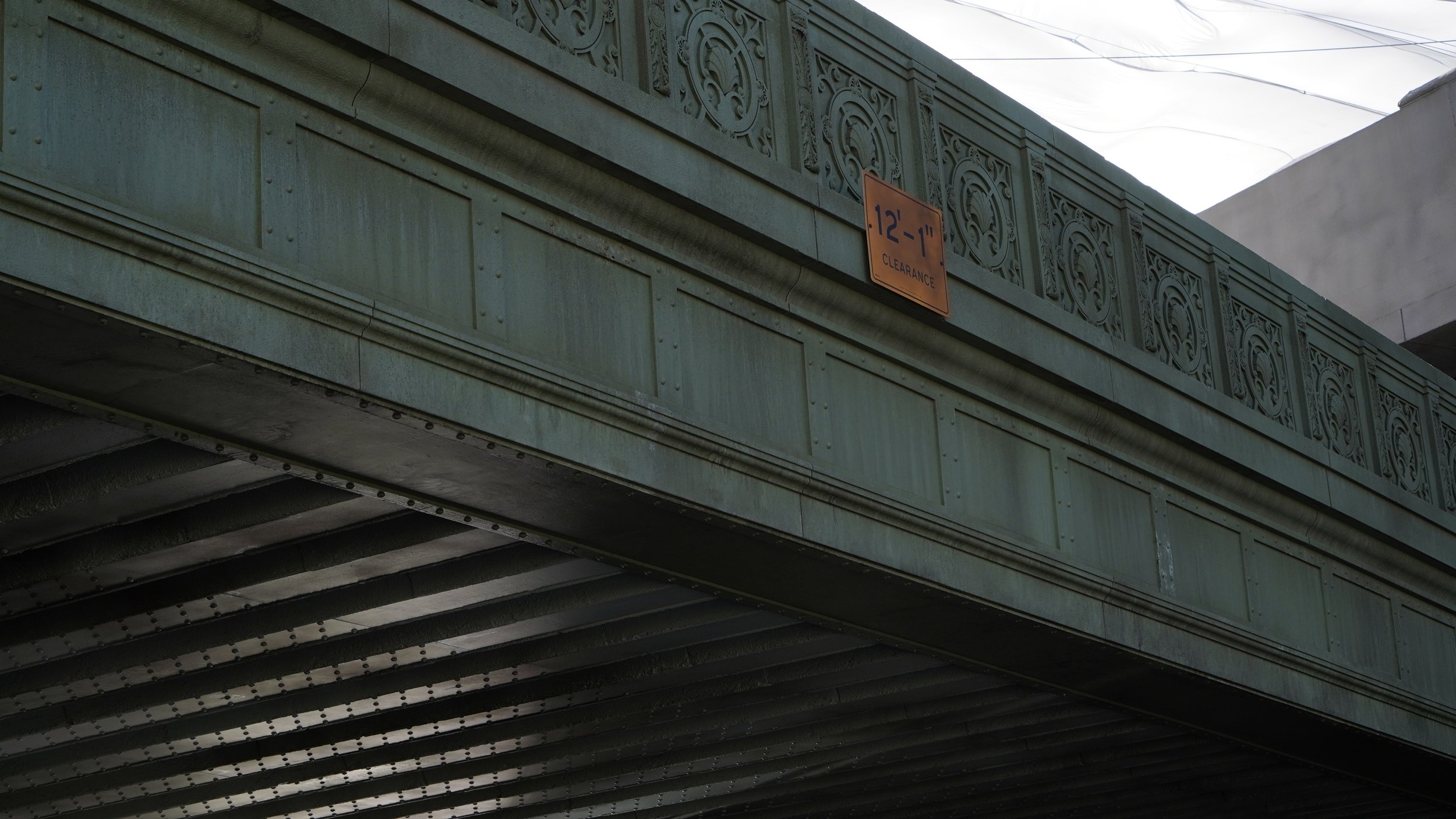 Close-up view of a bridge with a decorative railing and a clearance sign indicating 12 feet 1 inch.