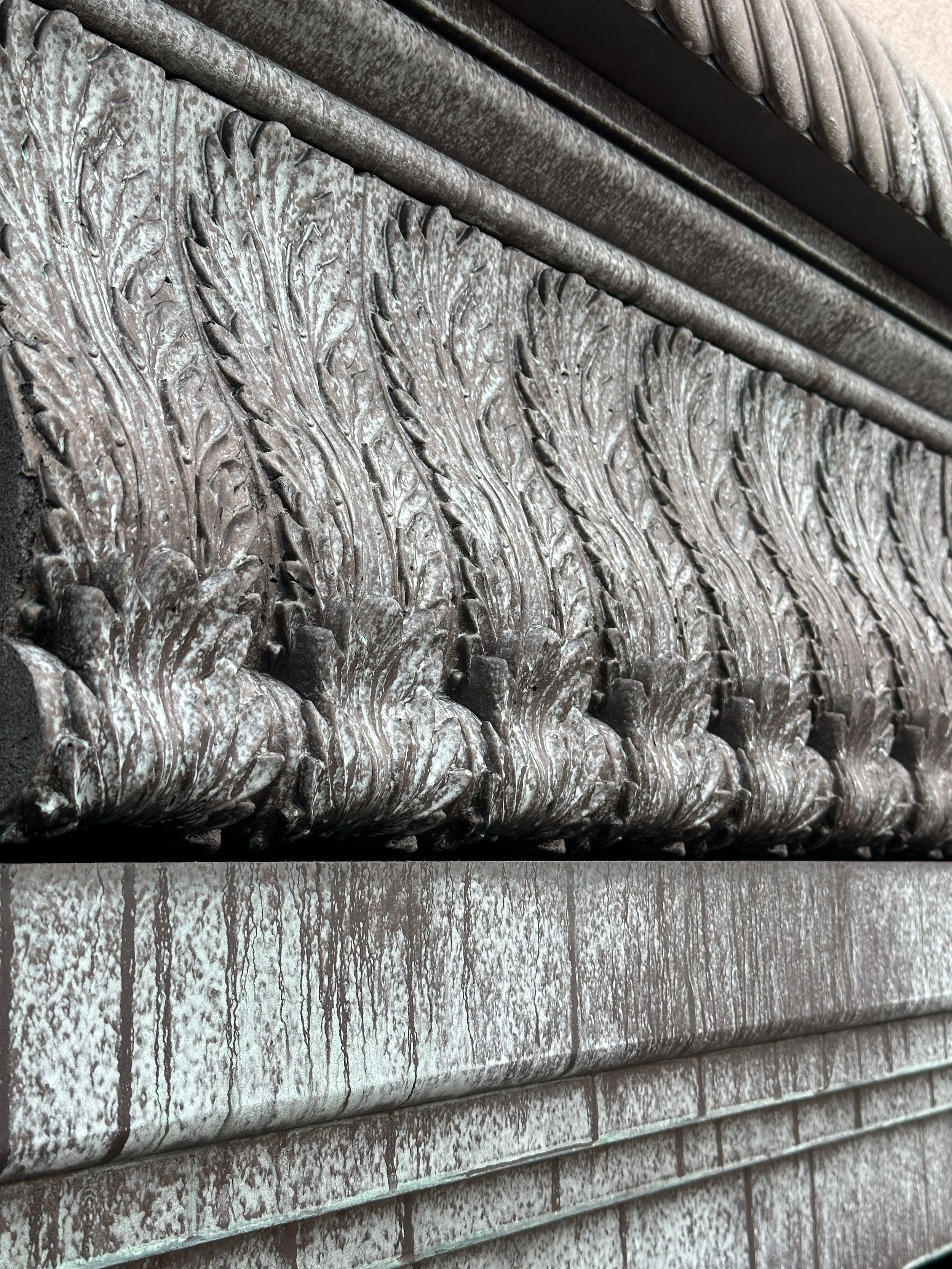 Close-up of ornate, carved stone details on a building's exterior wall, showing intricate patterns and textures.