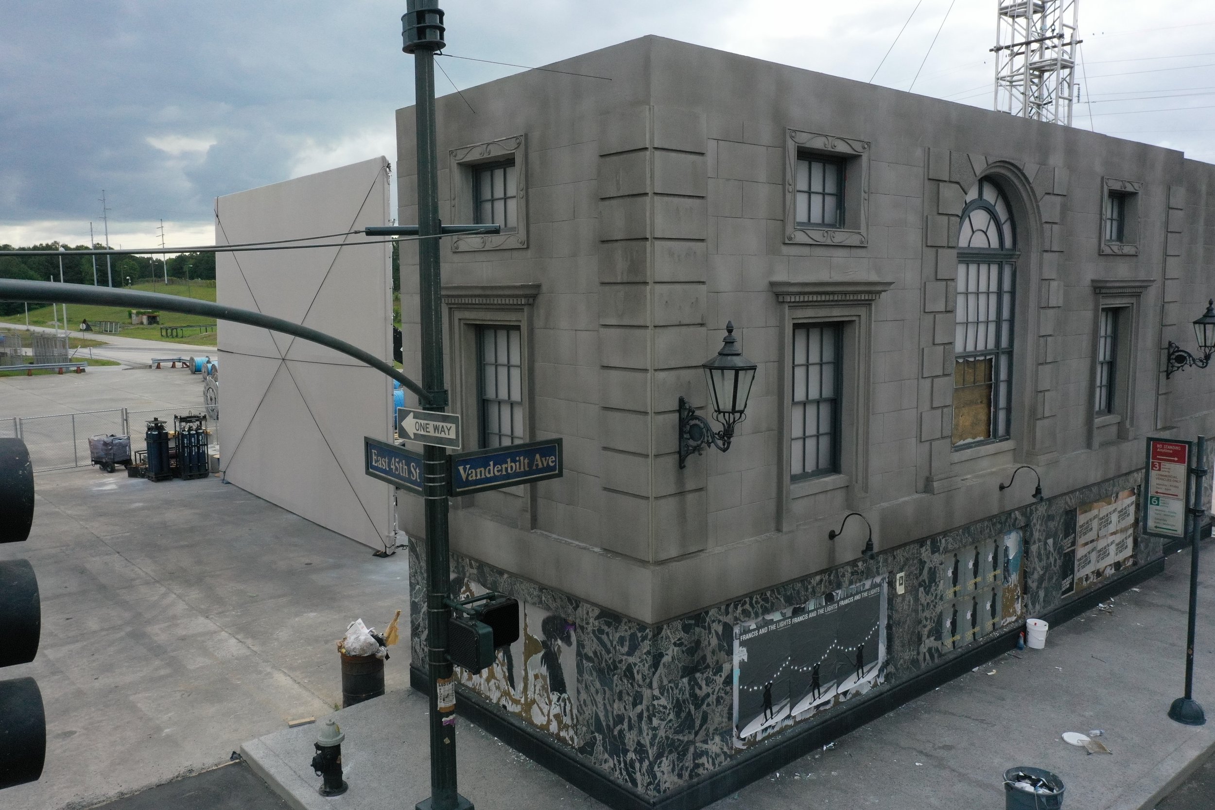Corner of a building on the intersection of East 45th Street and Vanderbilt Avenue with street signs, street lamps, and a mural of people ice skating on the lower wall.
