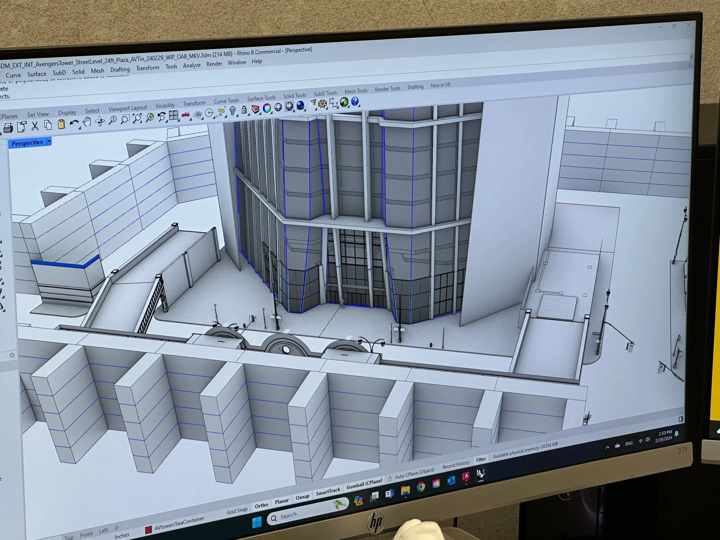 Computer-aided design (CAD) blueprints of a modern building with curved glass exterior walls displayed on a monitor.