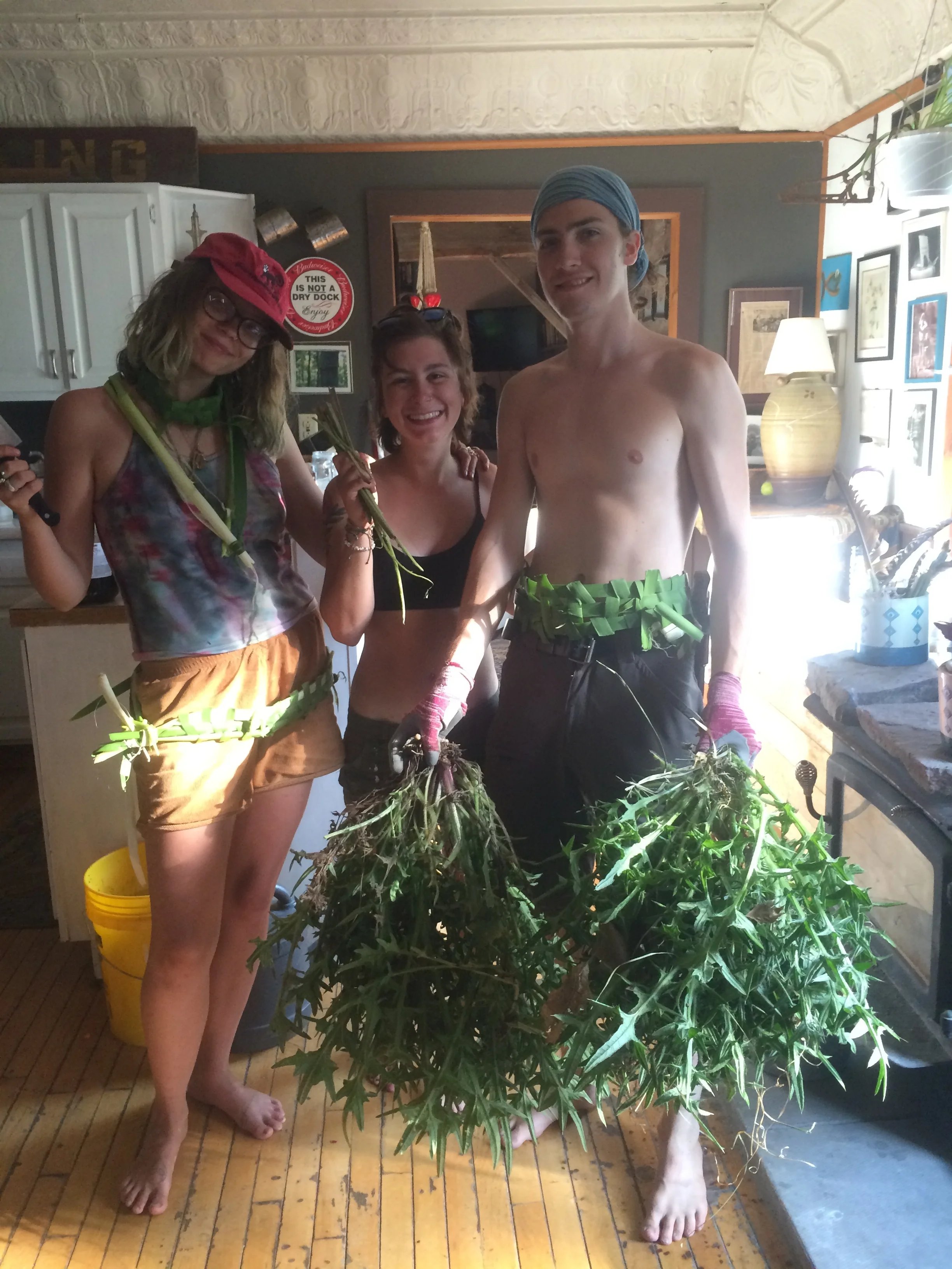 Students (from left) Nina, Steph and Levi display cattails and thistle harvested from the property.