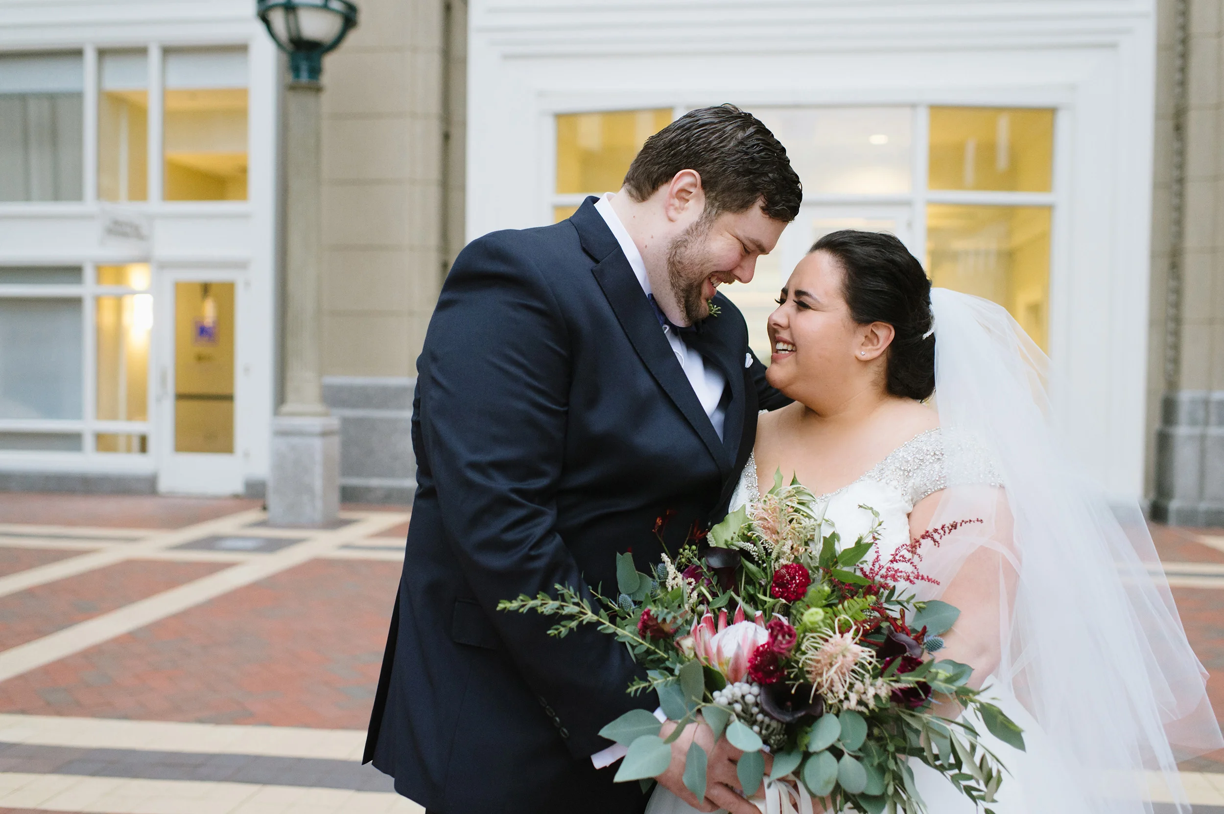 Bride and Groom laughing out in front of the Boston Harbor Hotel on their wedding day