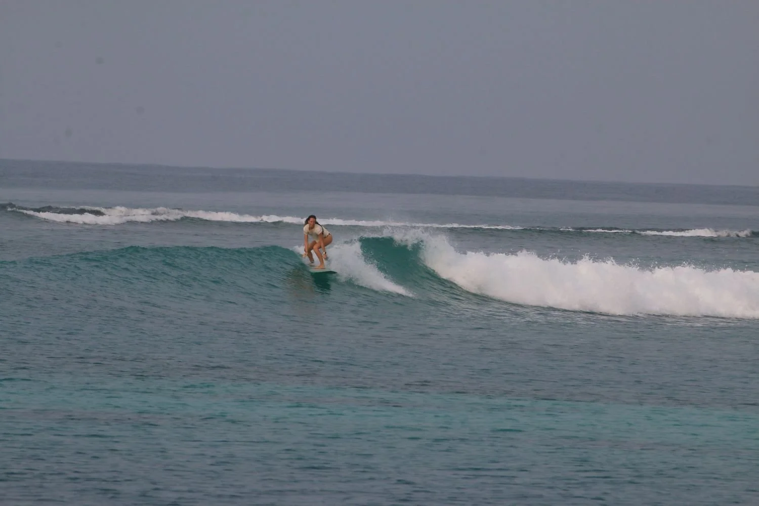 A person surfing on a small wave in the ocean.